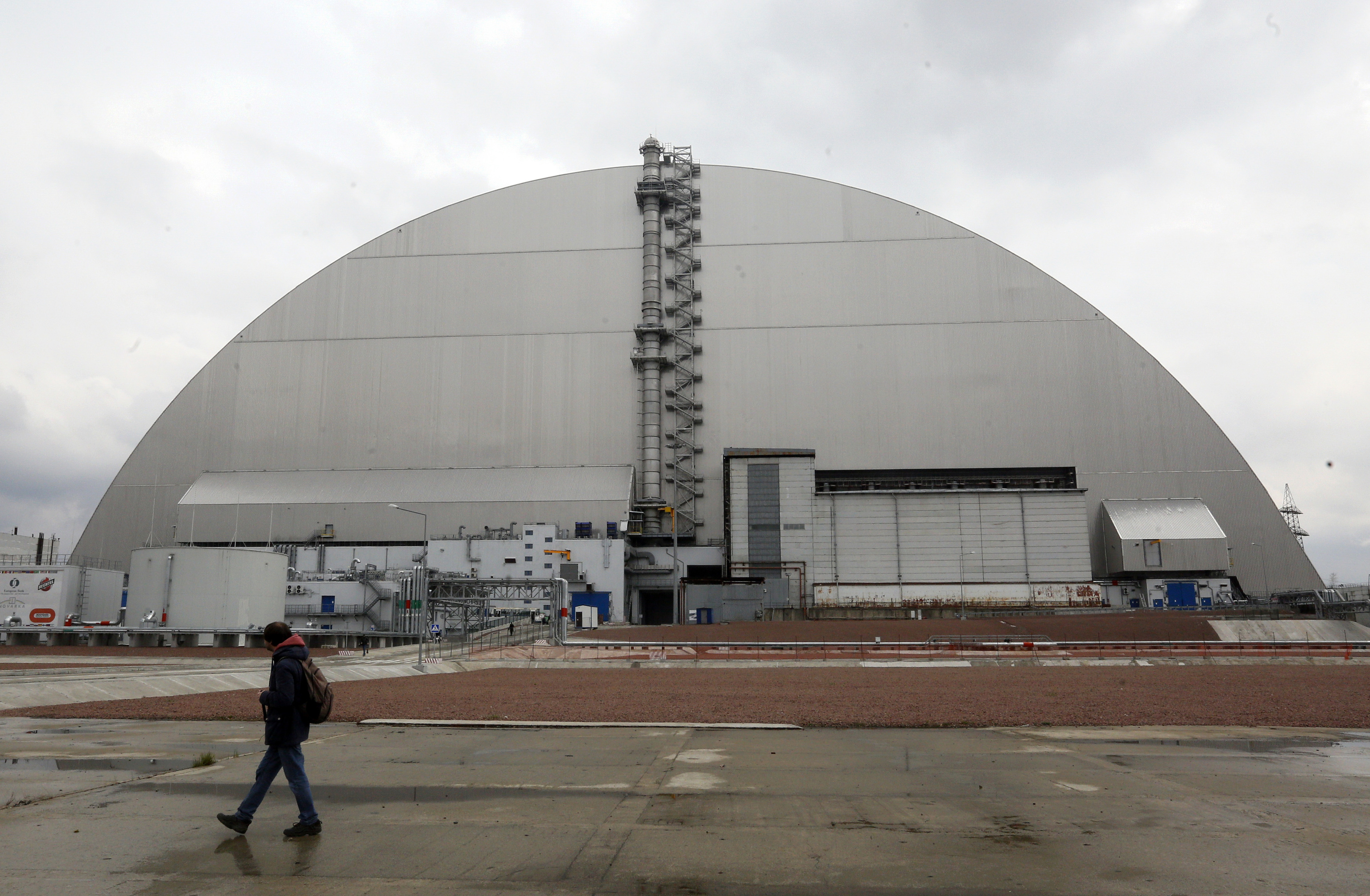 Un hombre camina junto a la cpula que cubre el reactor 4 de la central nuclear de Chernbil en una imagen de archivo.