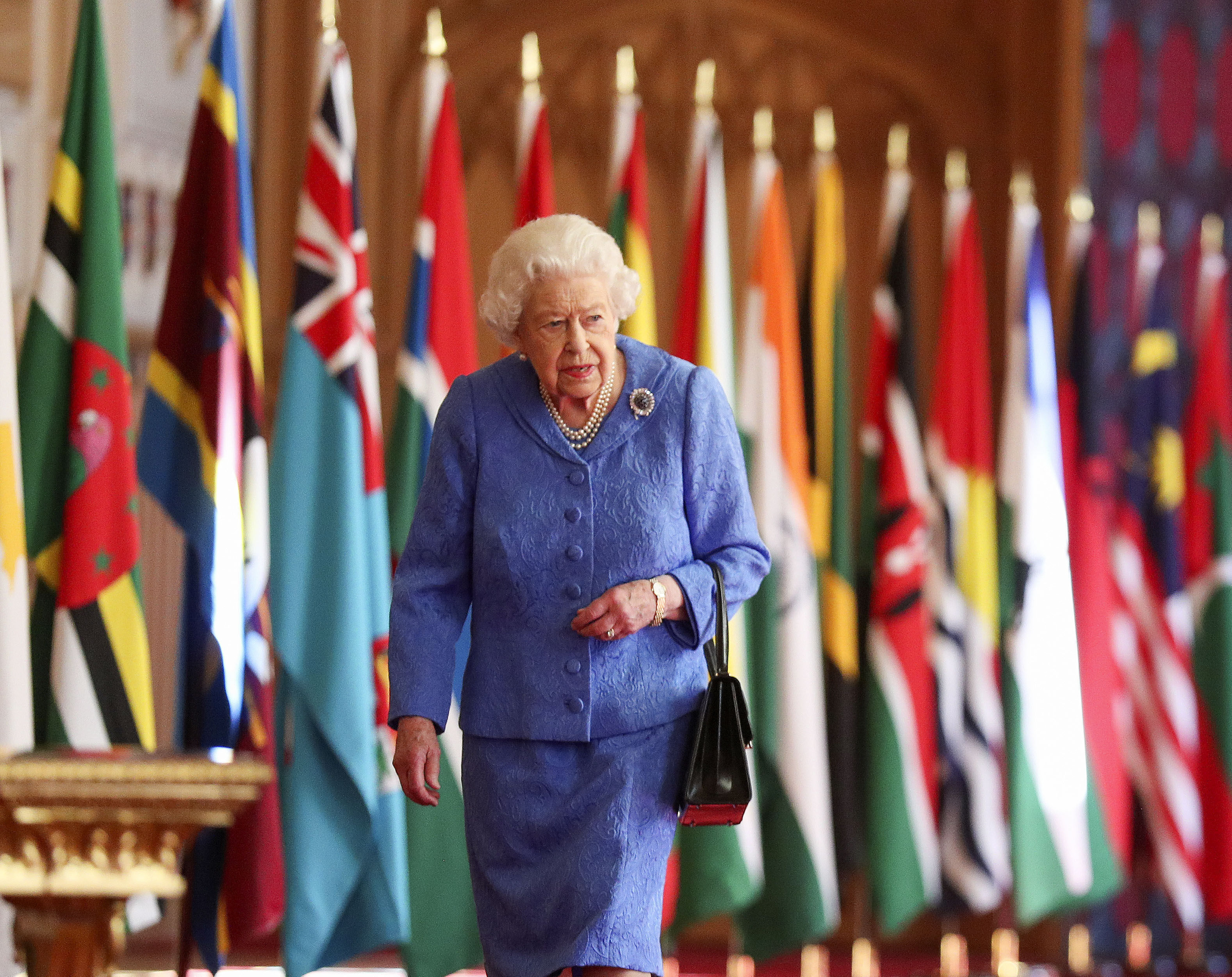 La reina Isabel II camina junto a las banderas de la Commonwealth en el Saln de San Jorge en el Castillo de Windsor, Inglaterra, para conmemorar el Da de la Commonwealth, en esta imagen que fue publicada el sbado 6 de marzo de 2021.
