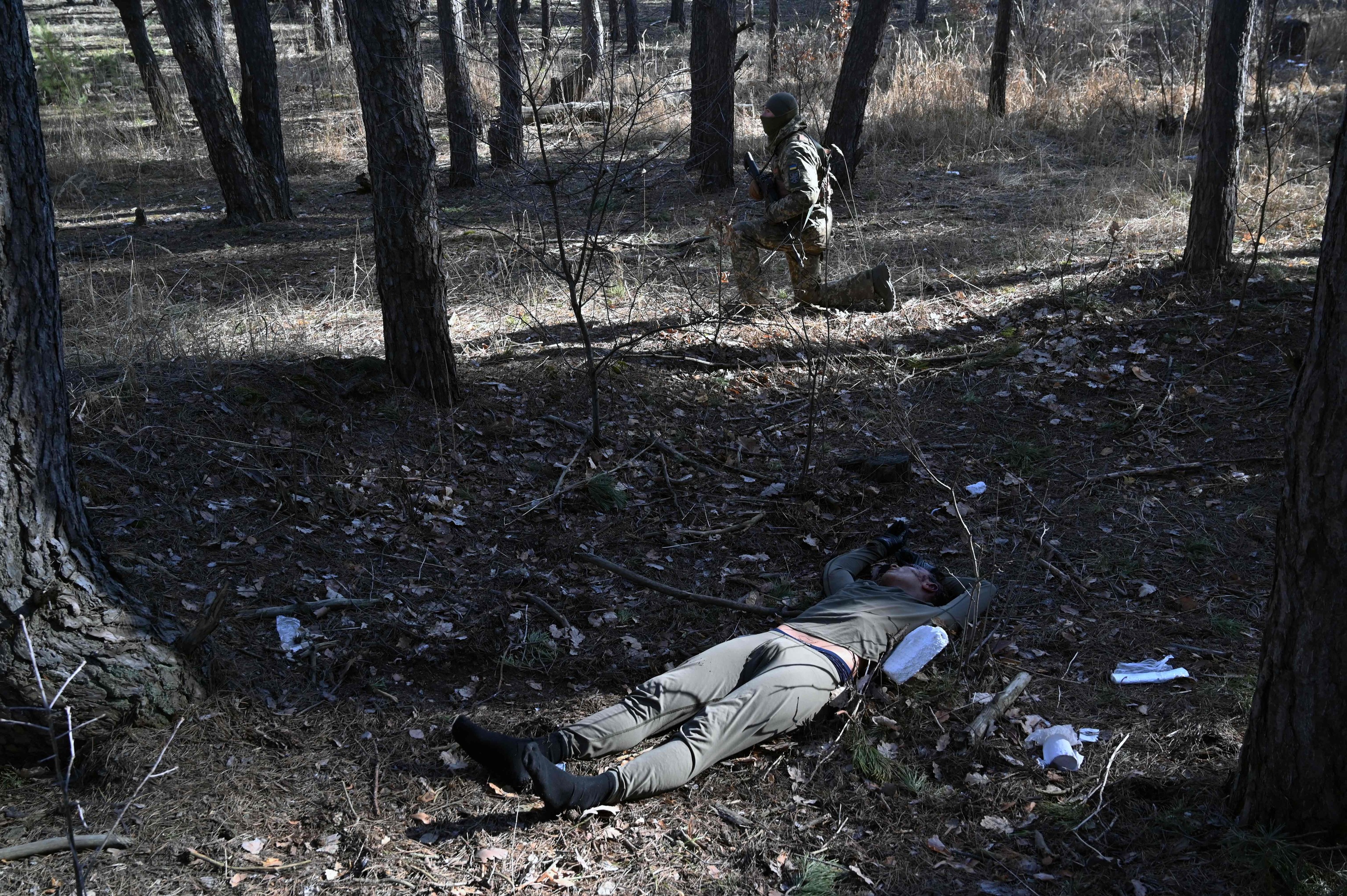Un soldado ucraniano mira hacia la posicin enemiga junto al cuerpo de un paracaidista ruso en Irpin, al norte de Kiev,