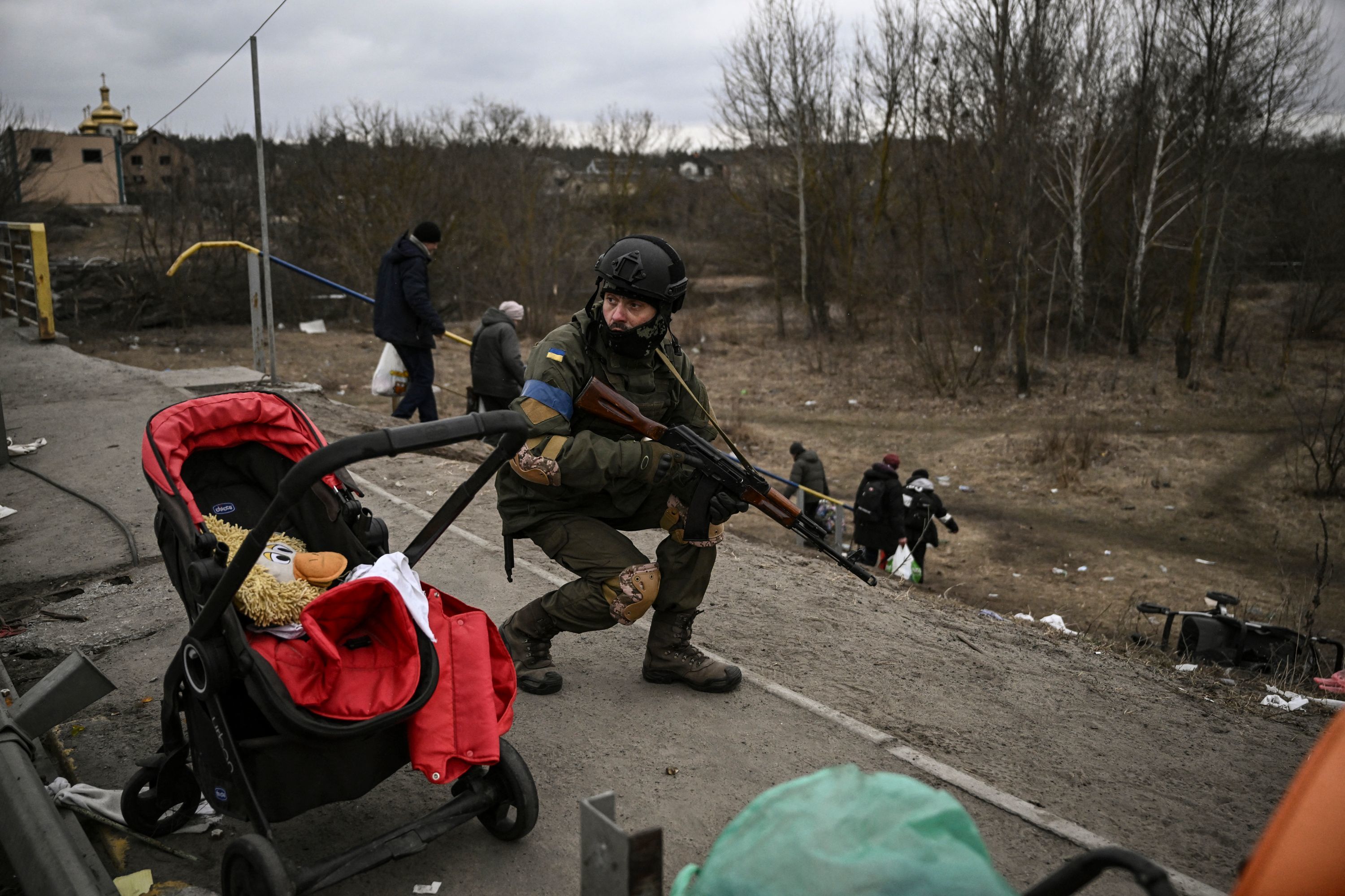 Un militar ucraniano se pone a cubierto mientras la poblacin huye de Irpin.