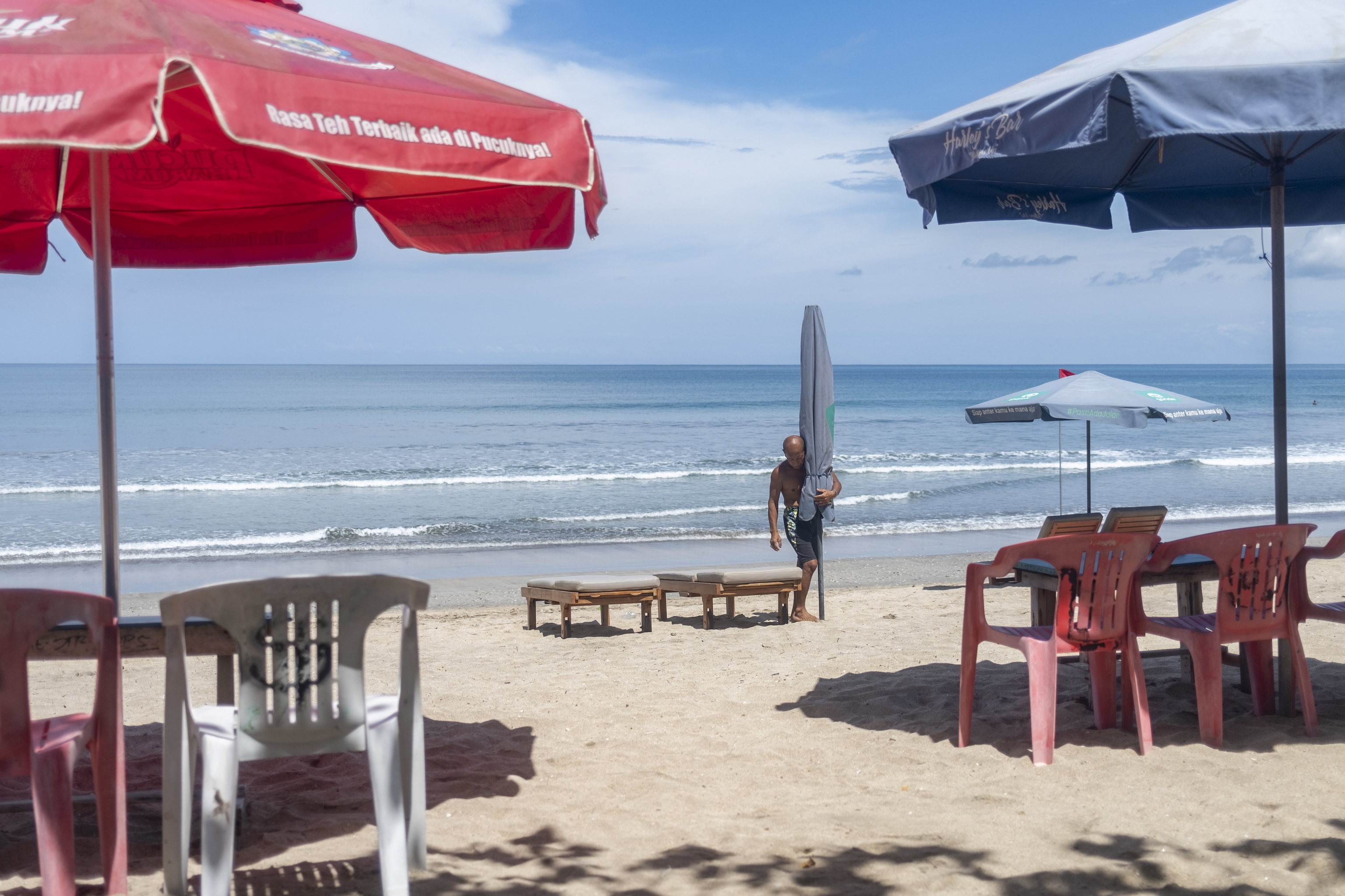 Un hombre arregla los asientos para los turistas en una playa de Kuta, Bali, Indonesia, el 11 de marzo de 2022. El gobierno indonesio puso en marcha el 7 de marzo una prueba de entrada sin cuarentena para los pasajeros internacionales que lleguen a Bali. En el marco del programa de prueba, se pretende levantar todas las normas de cuarentena para abril de 2022.