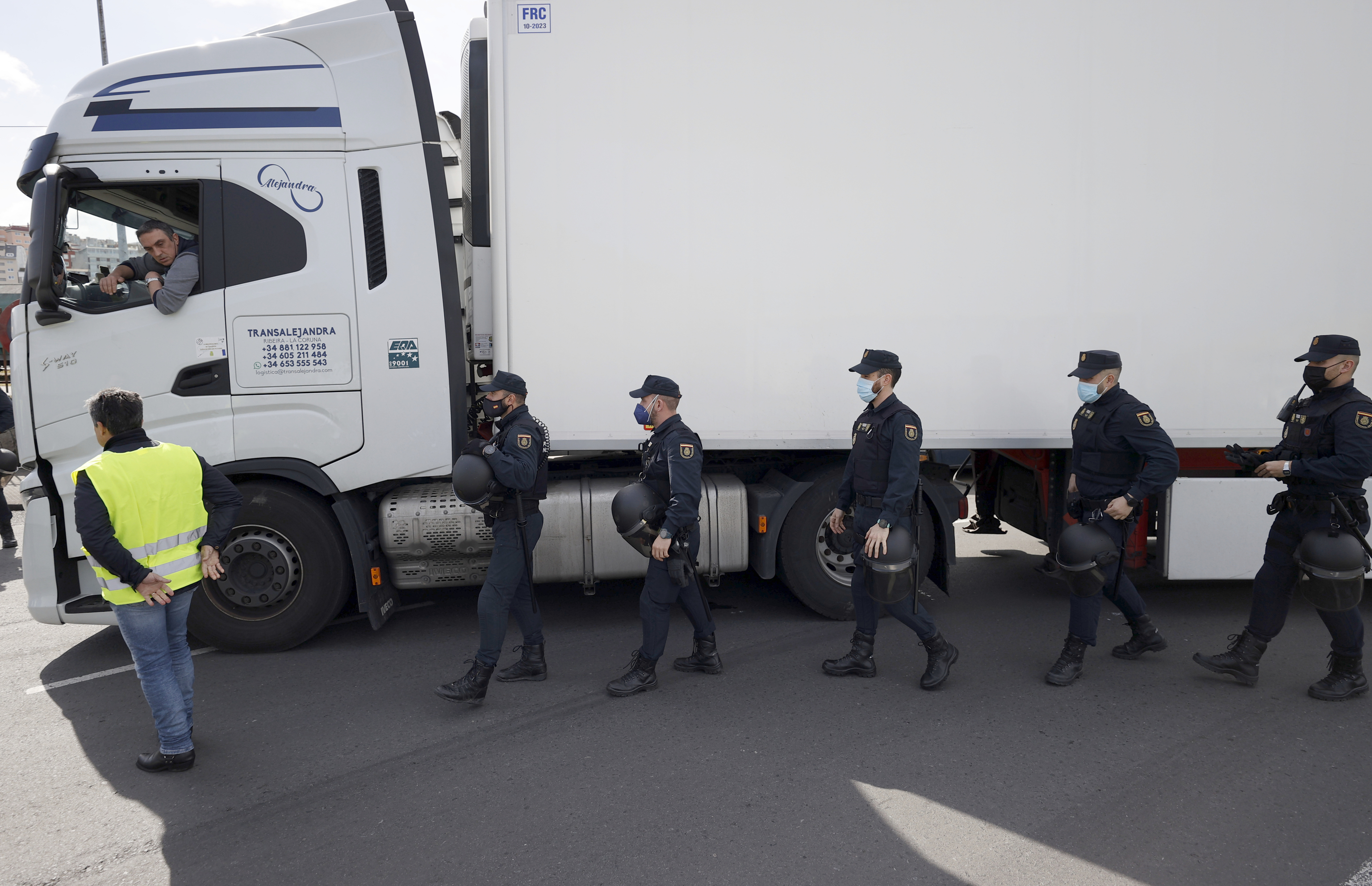 Policas escoltan a uno de los camiones que han salido del puerto de A Corua, donde un grupo de alrededor de 50 personas montaron un piquete informativo.