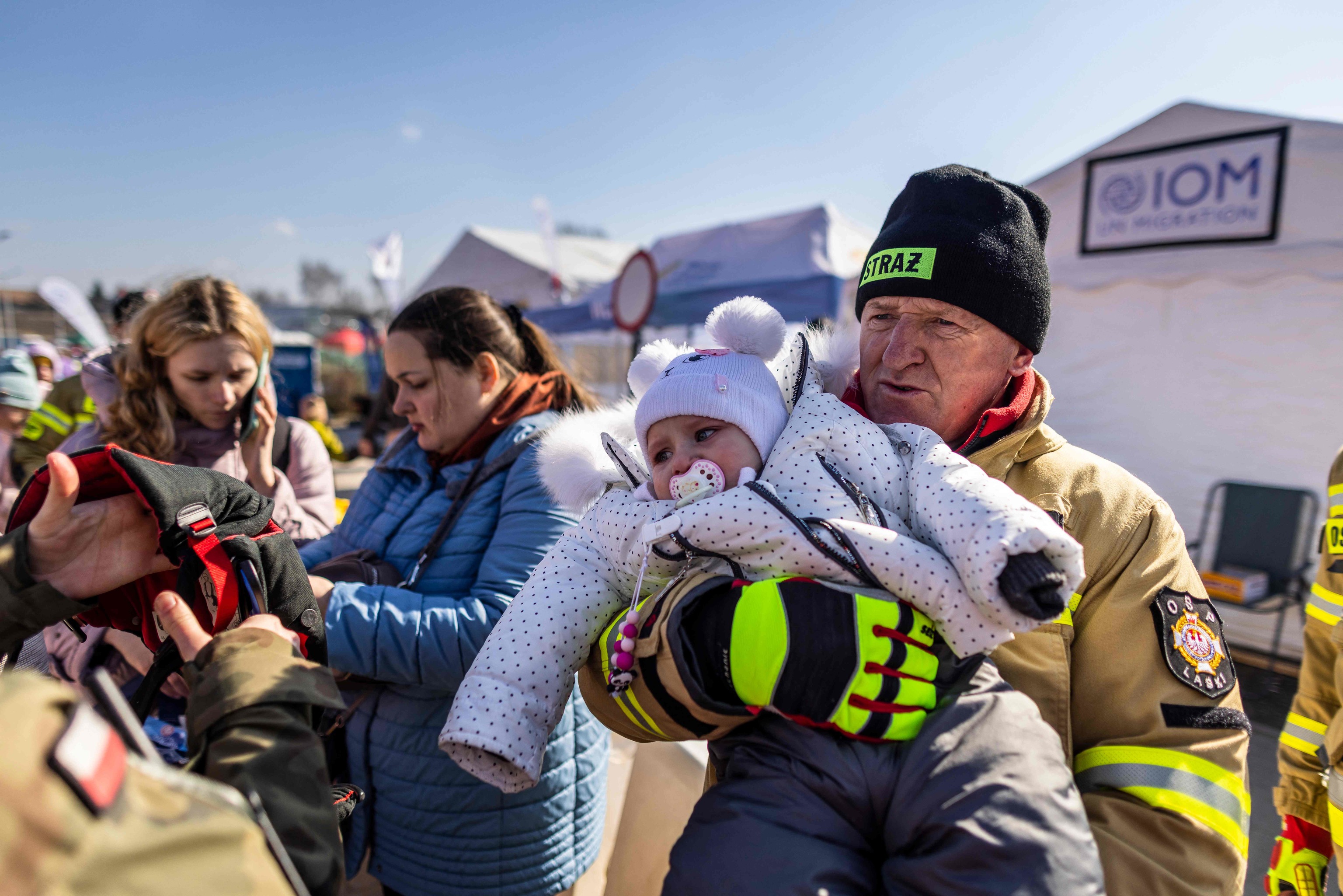 Un bombero polaco sostiene en sus brazos a un bebé en la frontera de Medyka (Polonia).