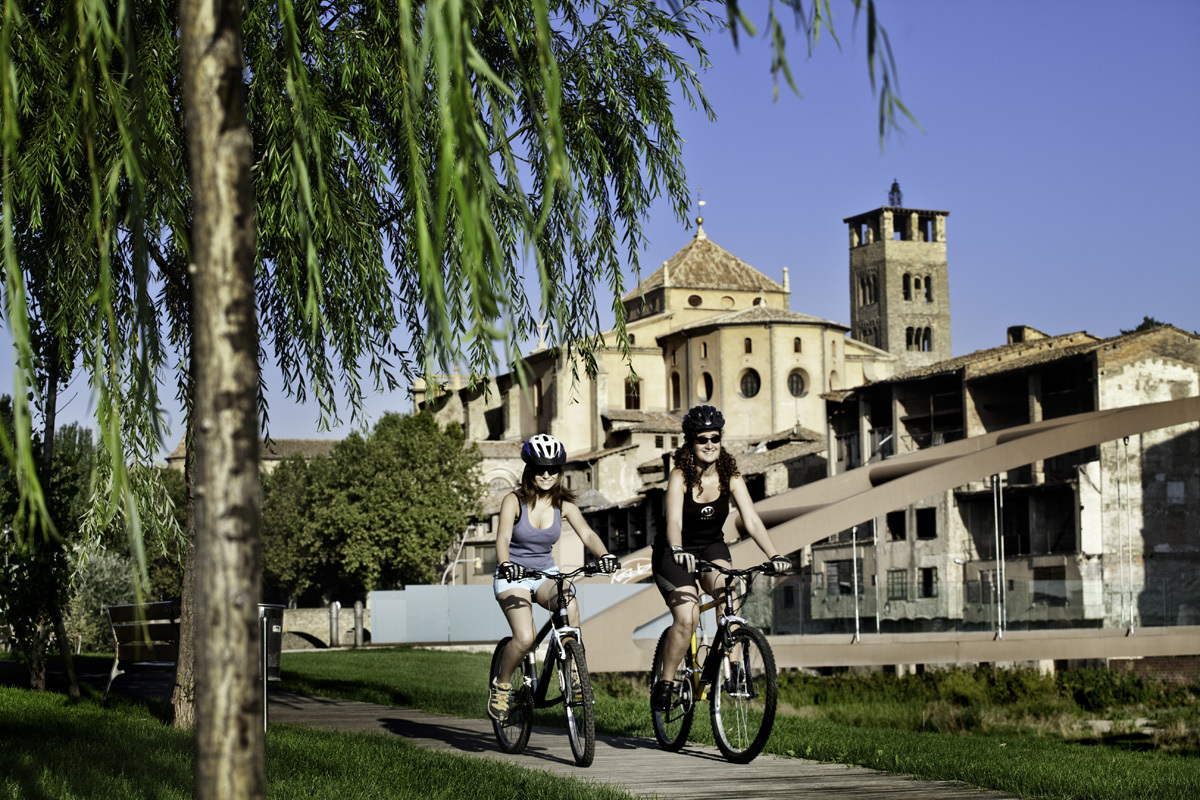 Dos ciclistas en uno de los paseos de Vic, con la catedral al fondo.