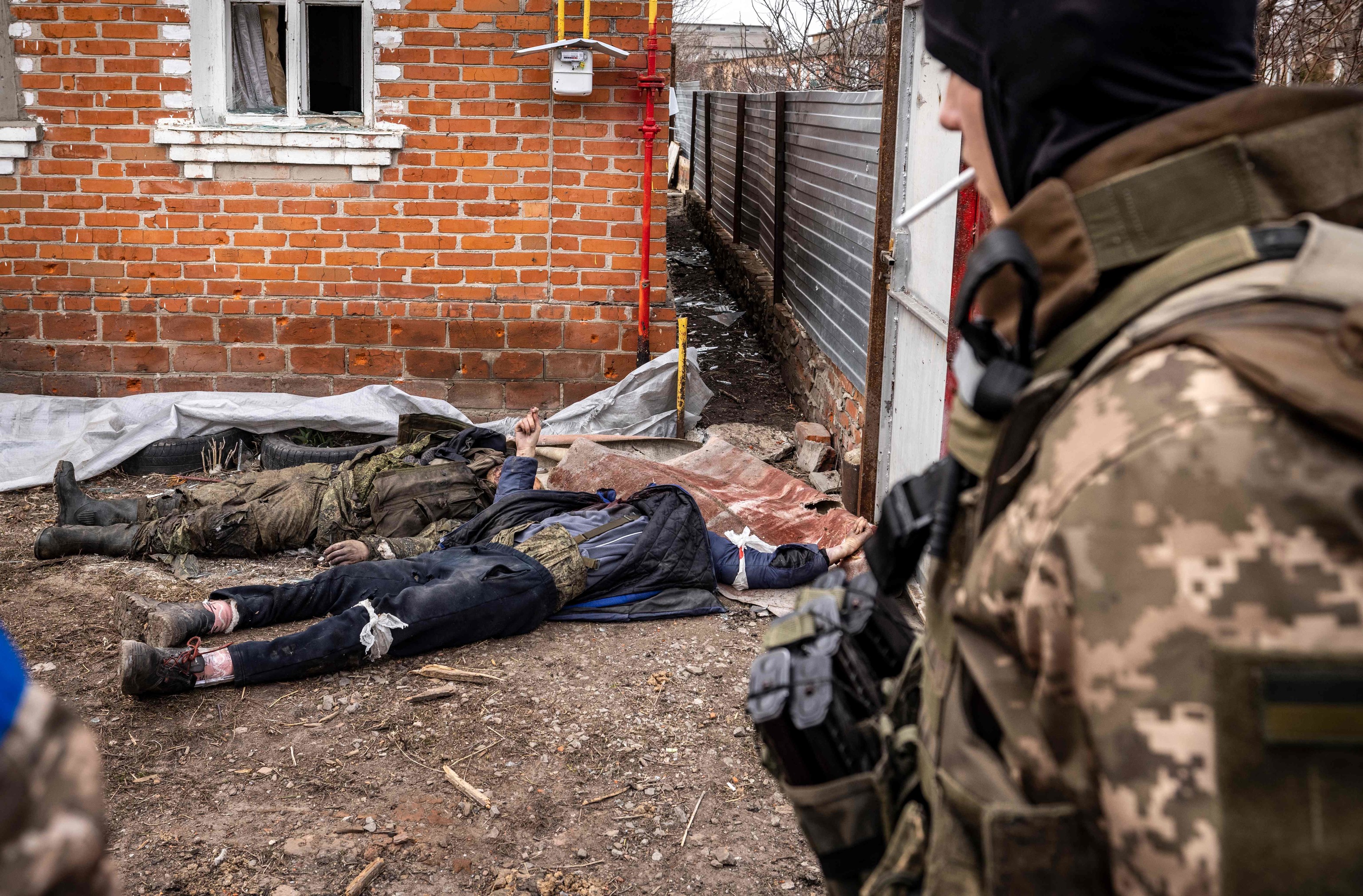 Un soldado ucraniano mira los cadáveres de dos soldados rusos.
