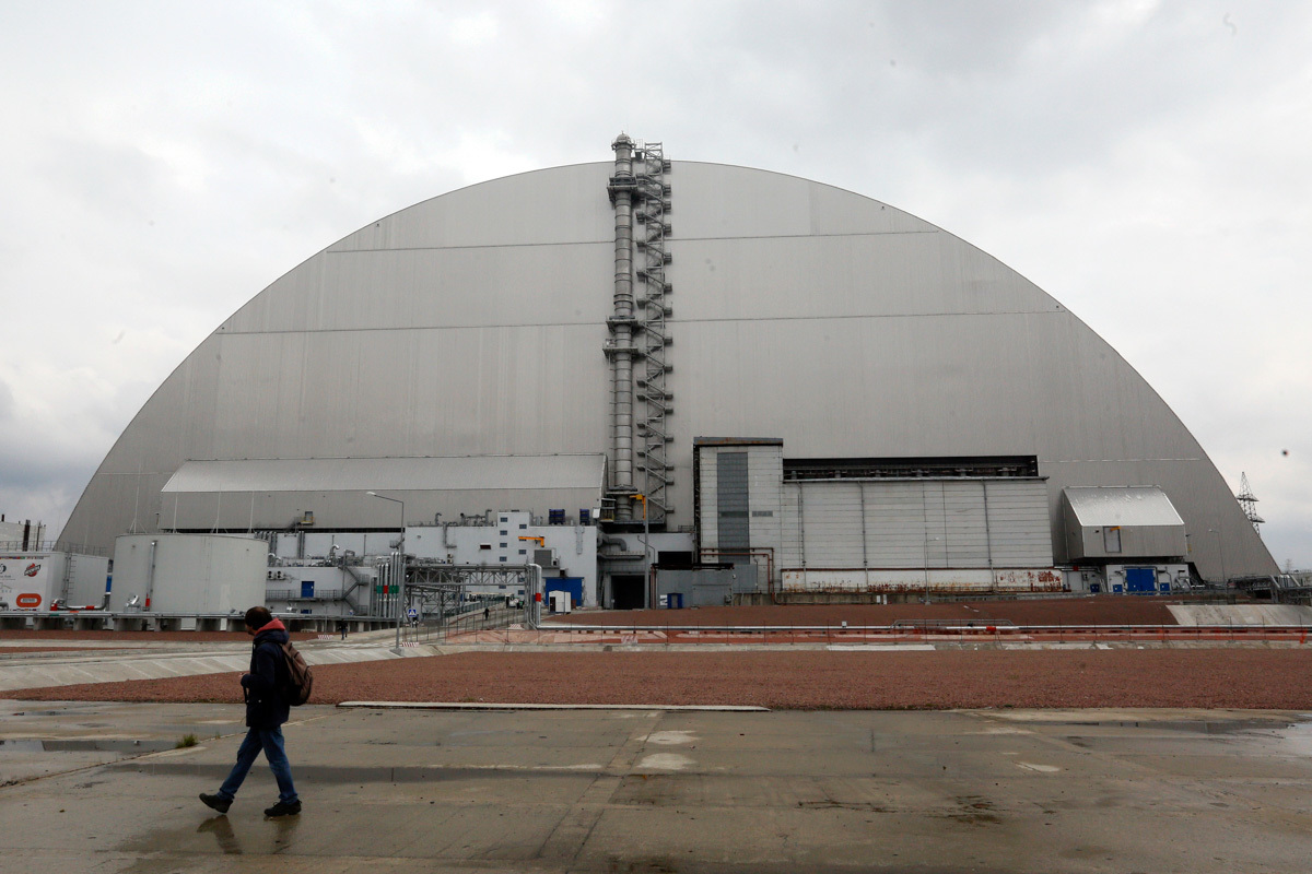 Un hombre pasa por delante de un refugio que cubre el reactor que explot en la central nuclear de Chernbil, el ao pasado.