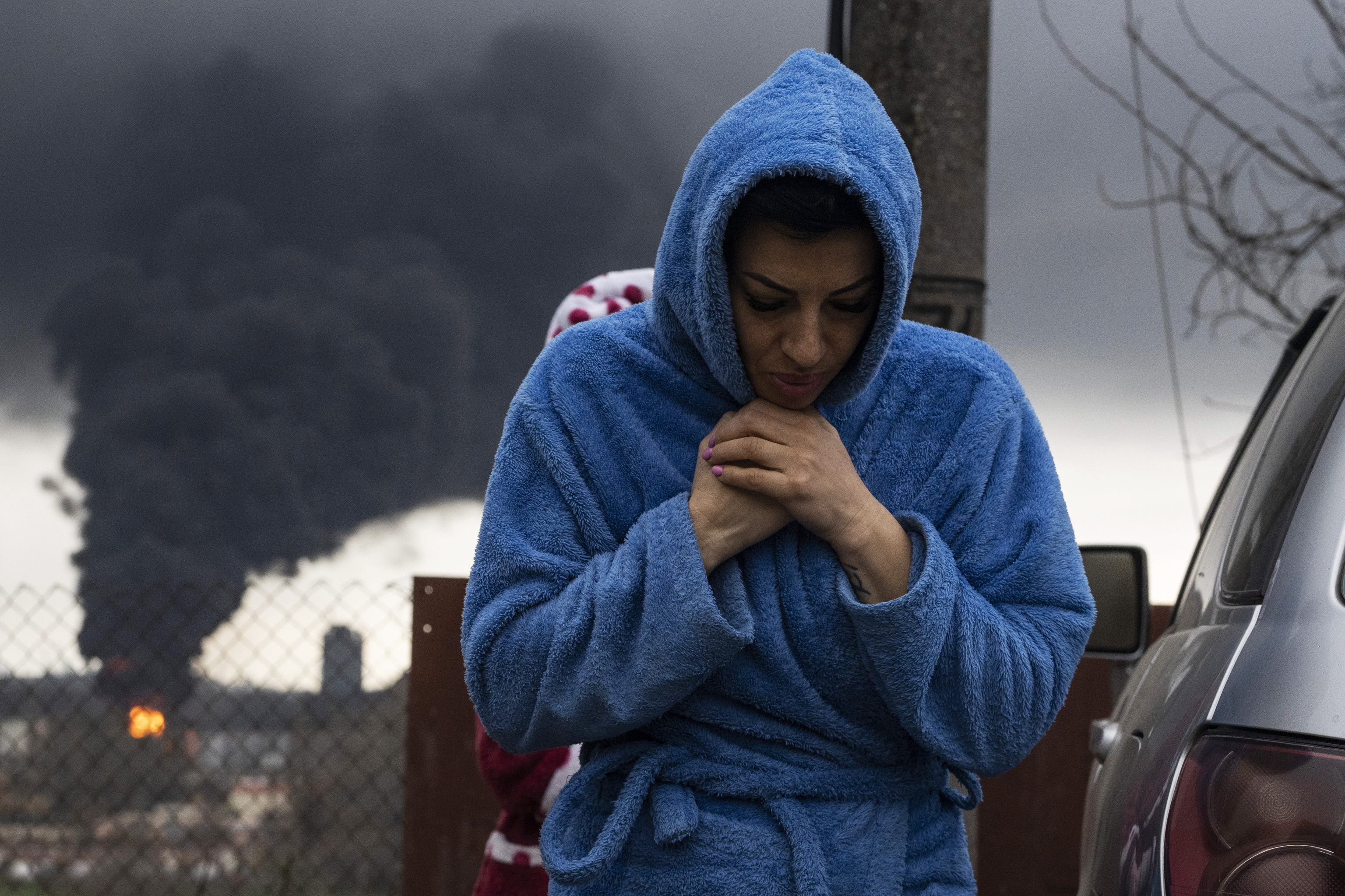 Una mujer camina por las calles de Odessa (Ucrania) con la refinería bombardeada por Rusia al fondo.