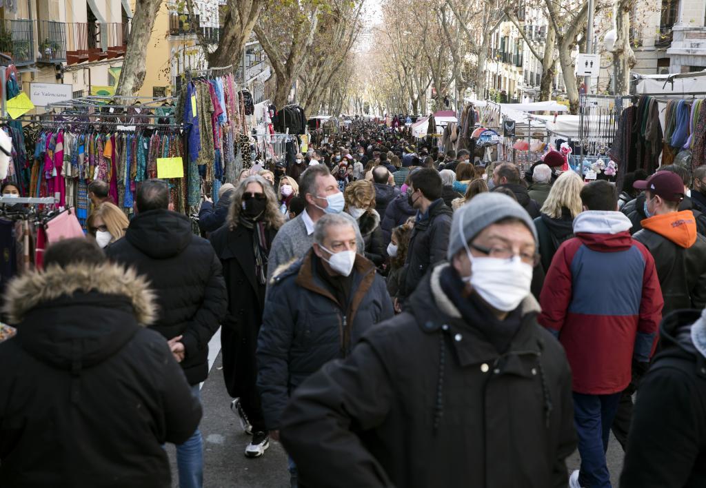 Varias personas pasean, protegidos con mascarillas, por el Rastro de Madrid.