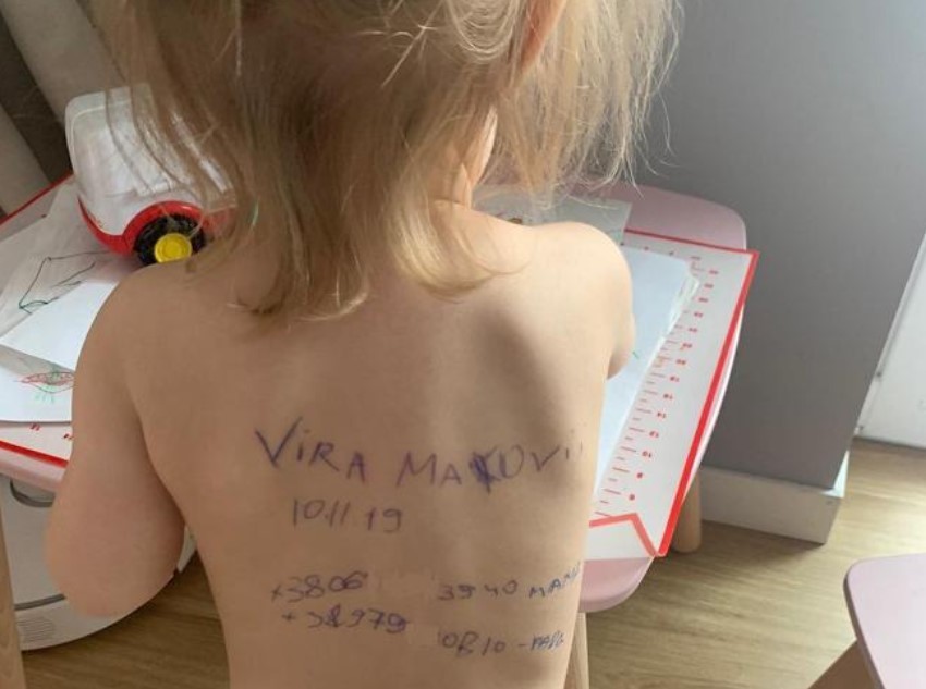 La espalda de Vira, con su nombre, nacimiento y los teléfonos de sus padres.