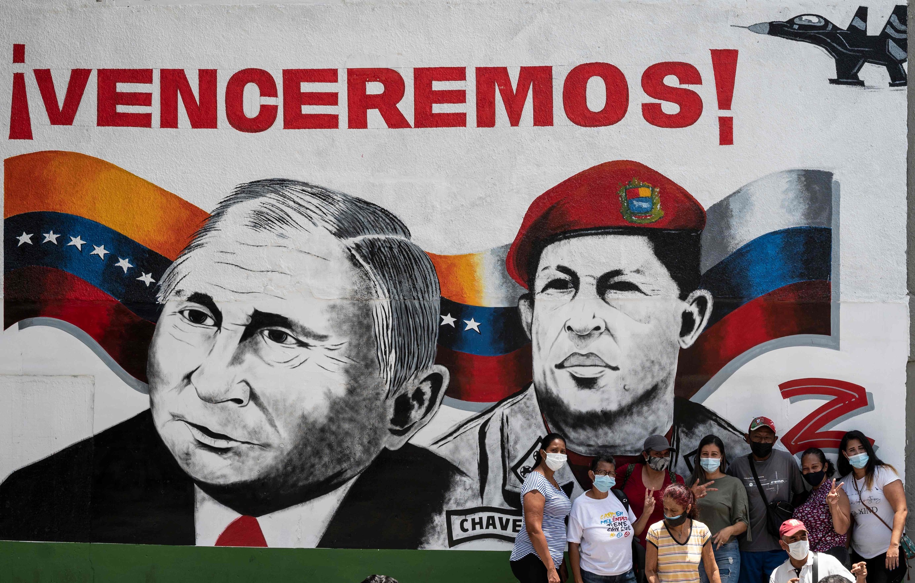Un grupo de residentes posa para una foto familiar frente a un mural con las caras de Putin y Chávez en Caracas.