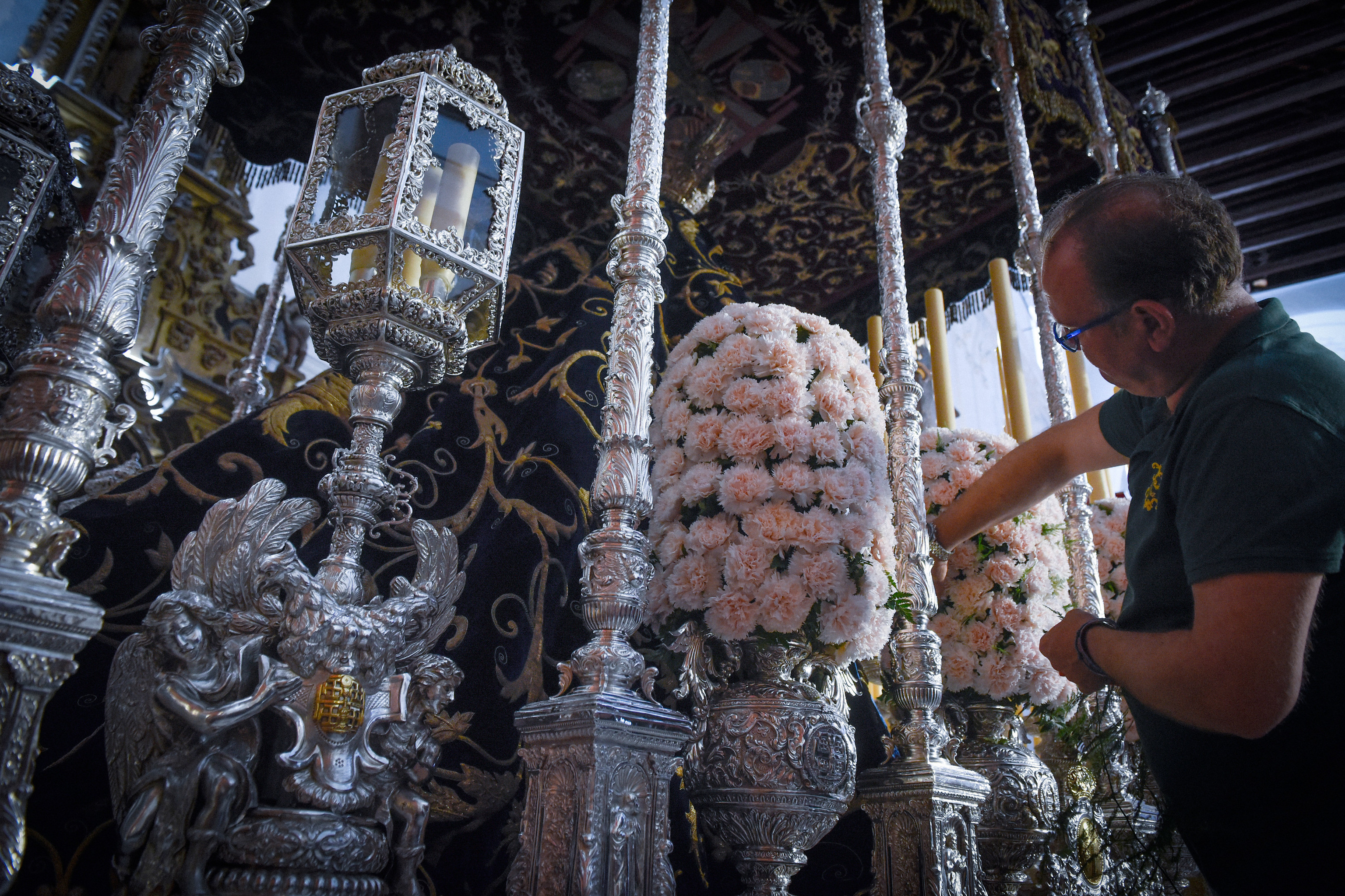 Un hombre ultima los adornos florales del paso de palio de la Virgen del Subterrneo de la Hermandad de la Cena de Sevilla.