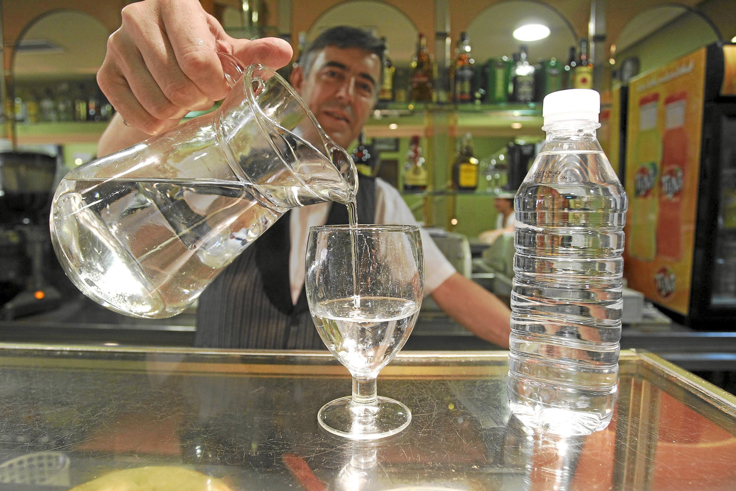 Un camarero sirve un vaso de agua en un bar de Madrid.