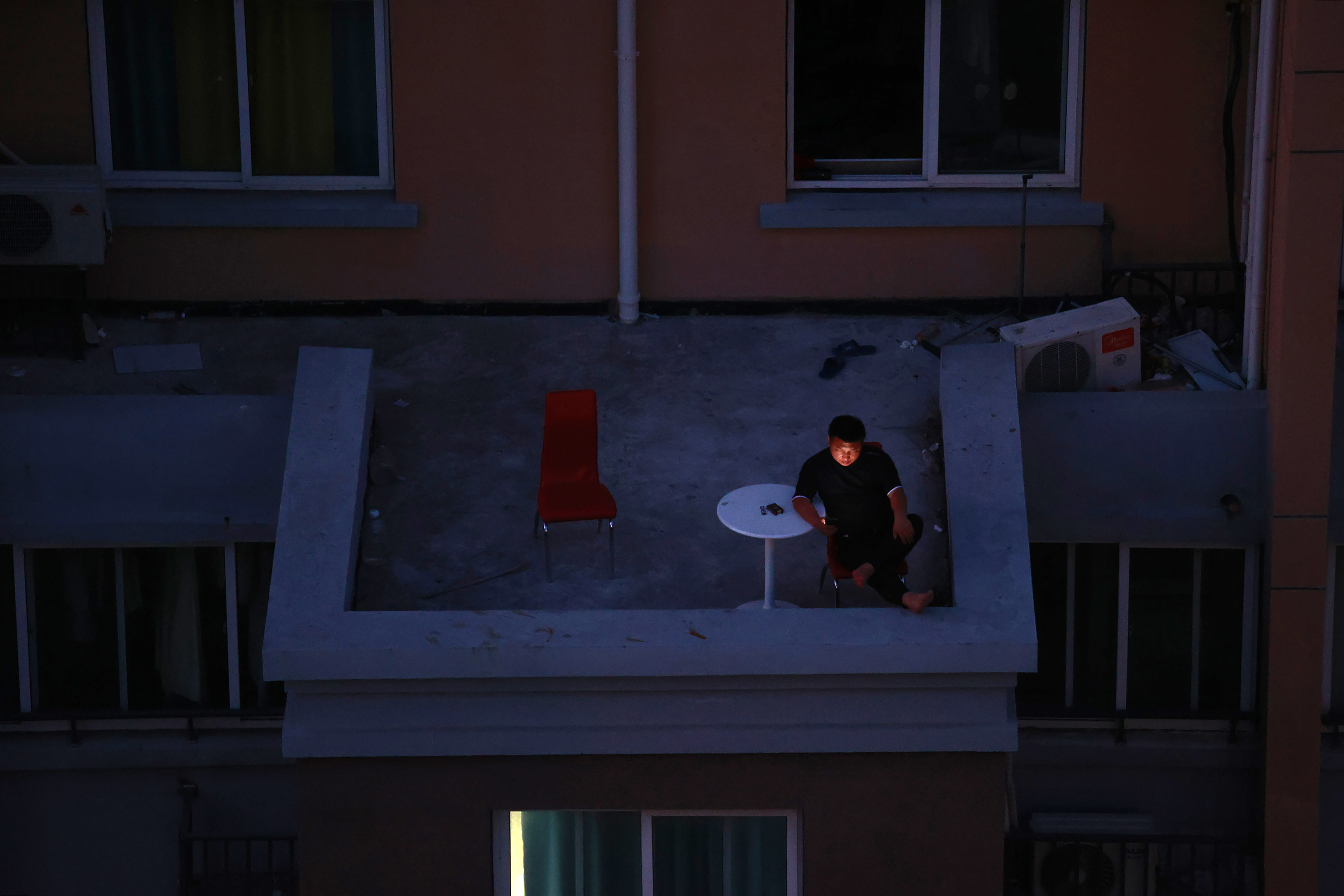 Un hombre mira su móvil en la terraza de su casa, en Shangai.