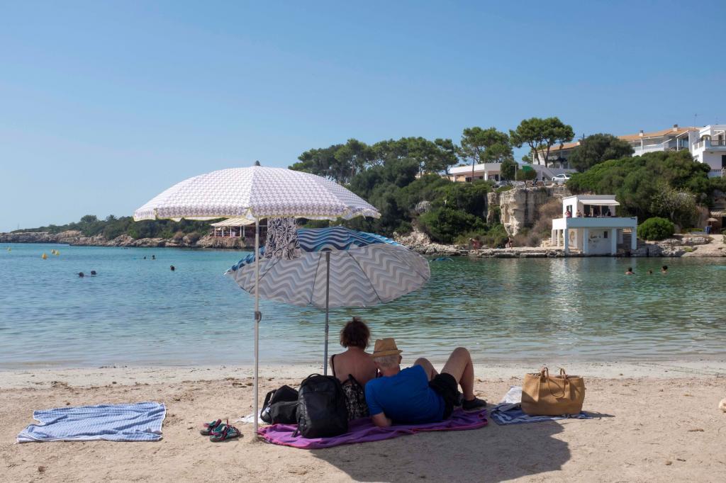 Una pareja toma el sol en la Cala Santandría de Menorca en agosto del año pasado.