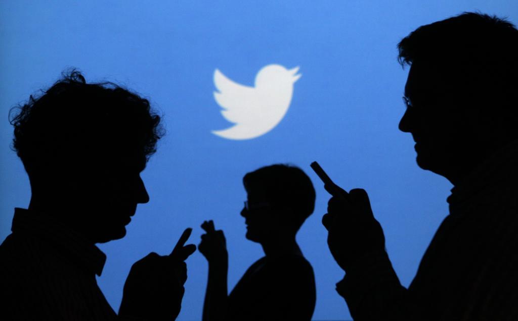 Varias personas con sus móviles ante un logotipo de Twitter.