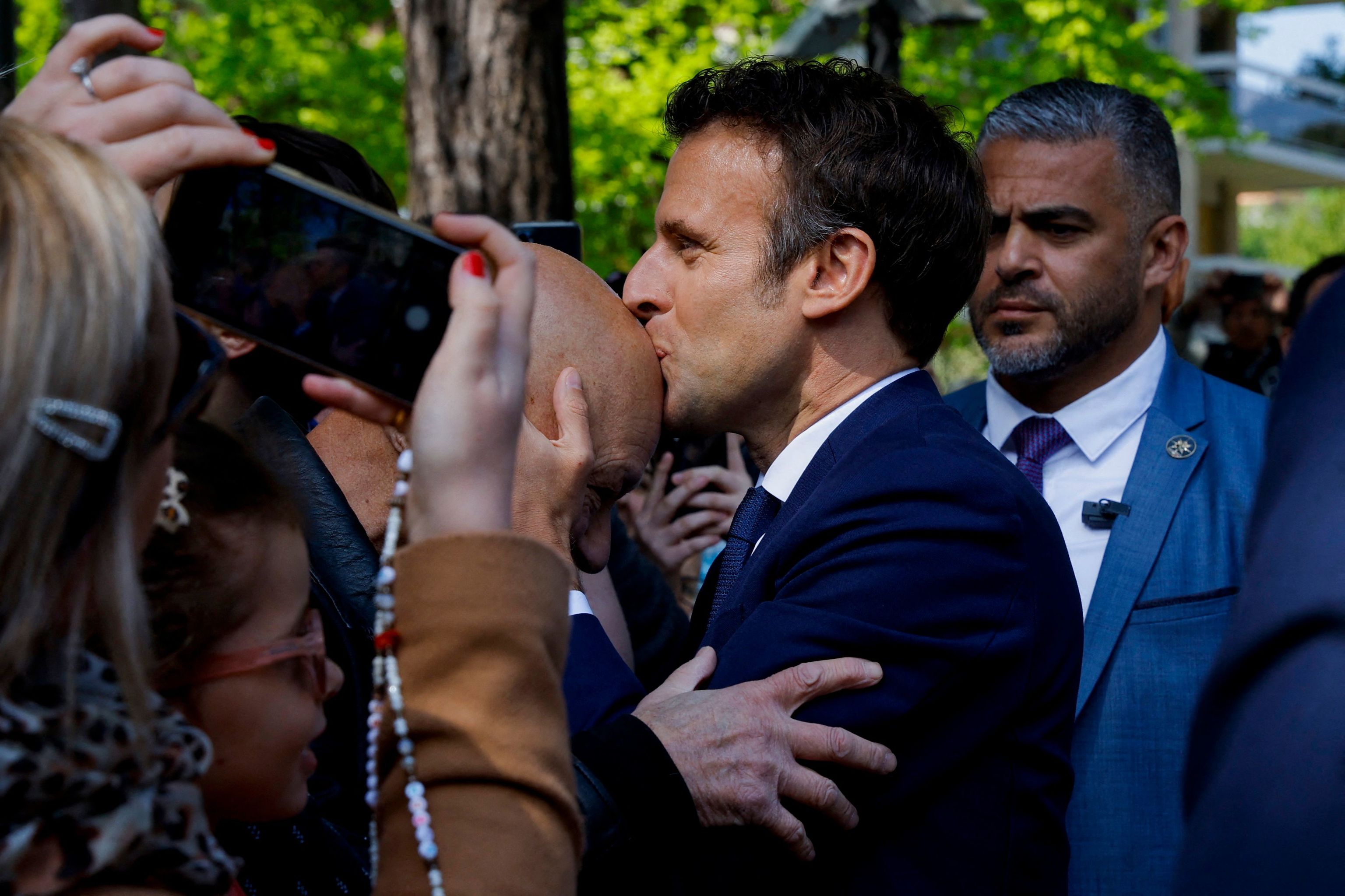 TOPSHOT - France's President and LREM party presidential candidate Emmanuel  lt;HIT gt;Macron lt;/HIT gt; kisses a supporter as he arrives to vote for the second round of France's presidential election at a polling station in Le Touquet, northern France, on April 24, 2022. (Photo by GONZALO FUENTES / POOL / AFP)