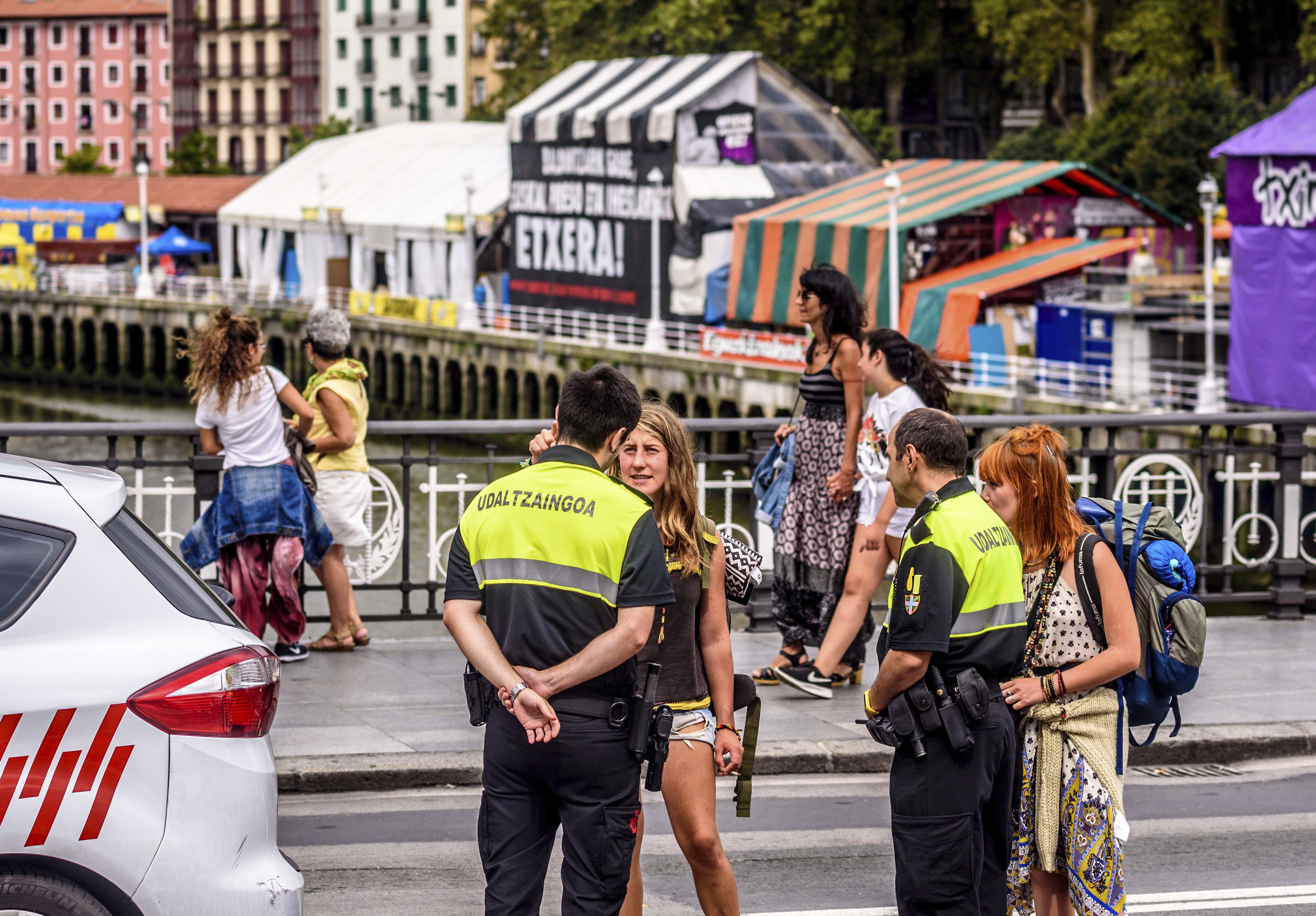Dos agentes de la Polica Municipal de Bilbao atienden a dos turistas durante la celebracin de la Aste Nagusia en el puente del Arenal.