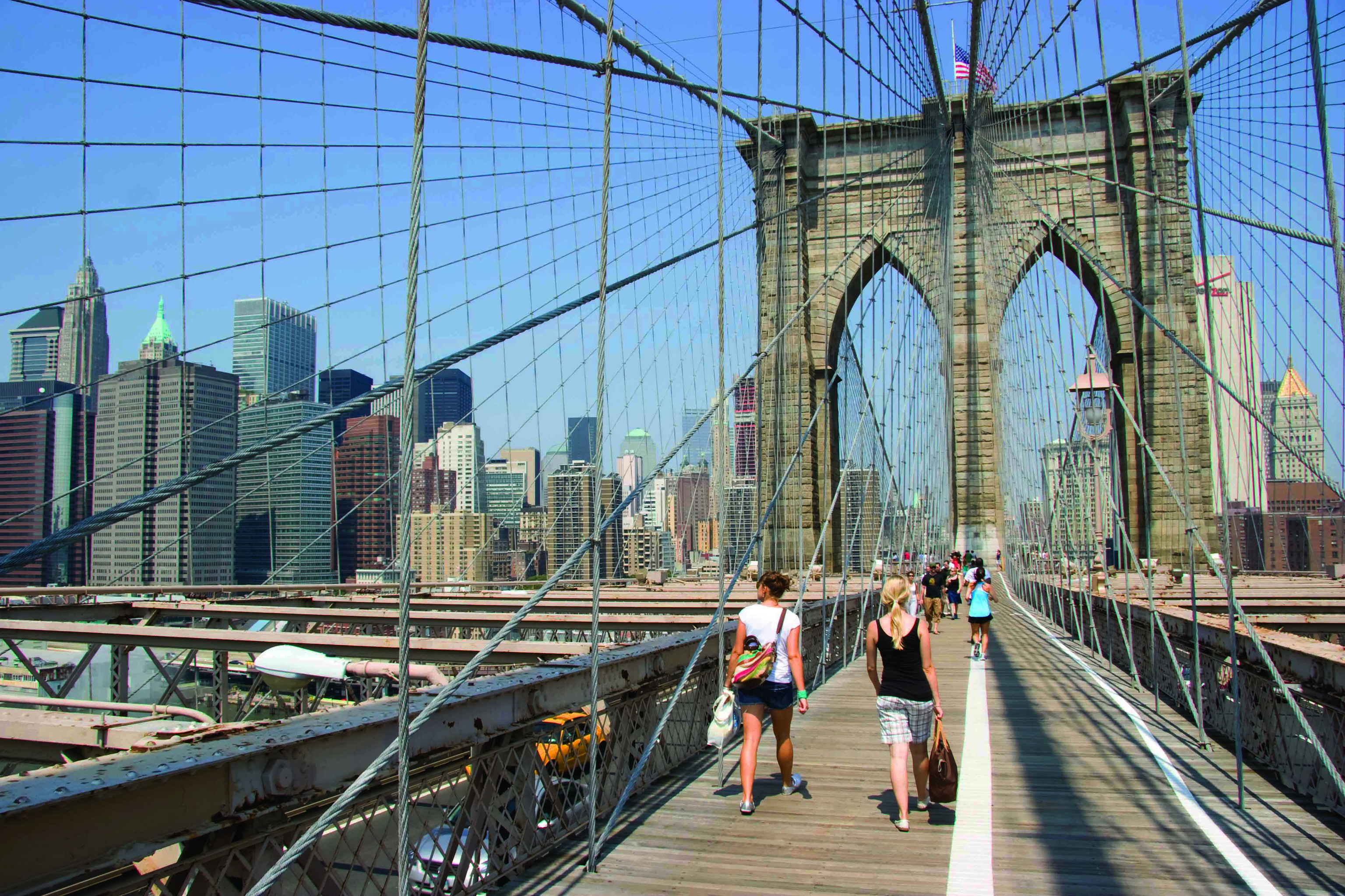 Varios personas caminan sobre el puente de Brooklyn.