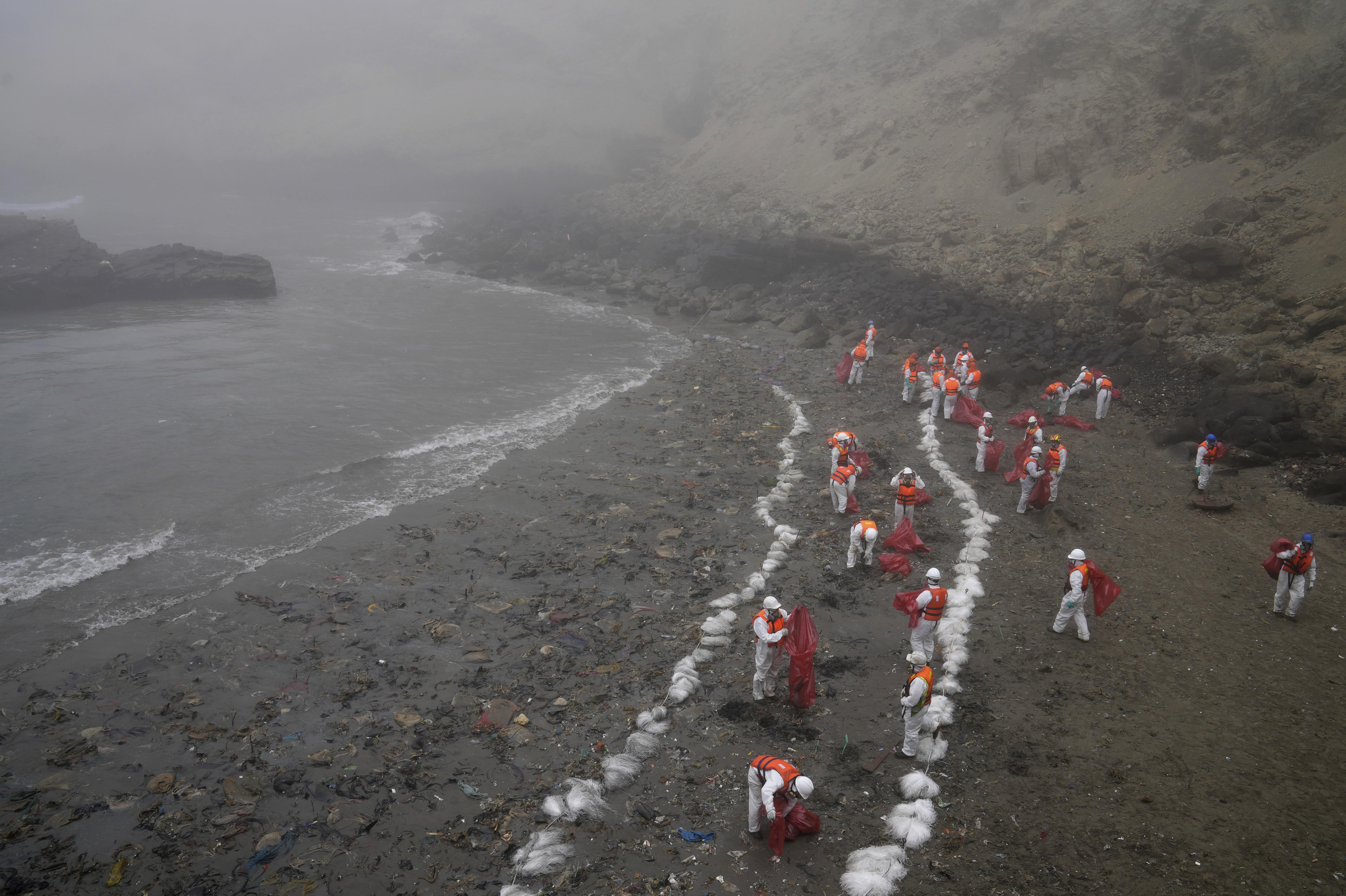 Several workers clean up Pocitos beach in Ancon, Peru.