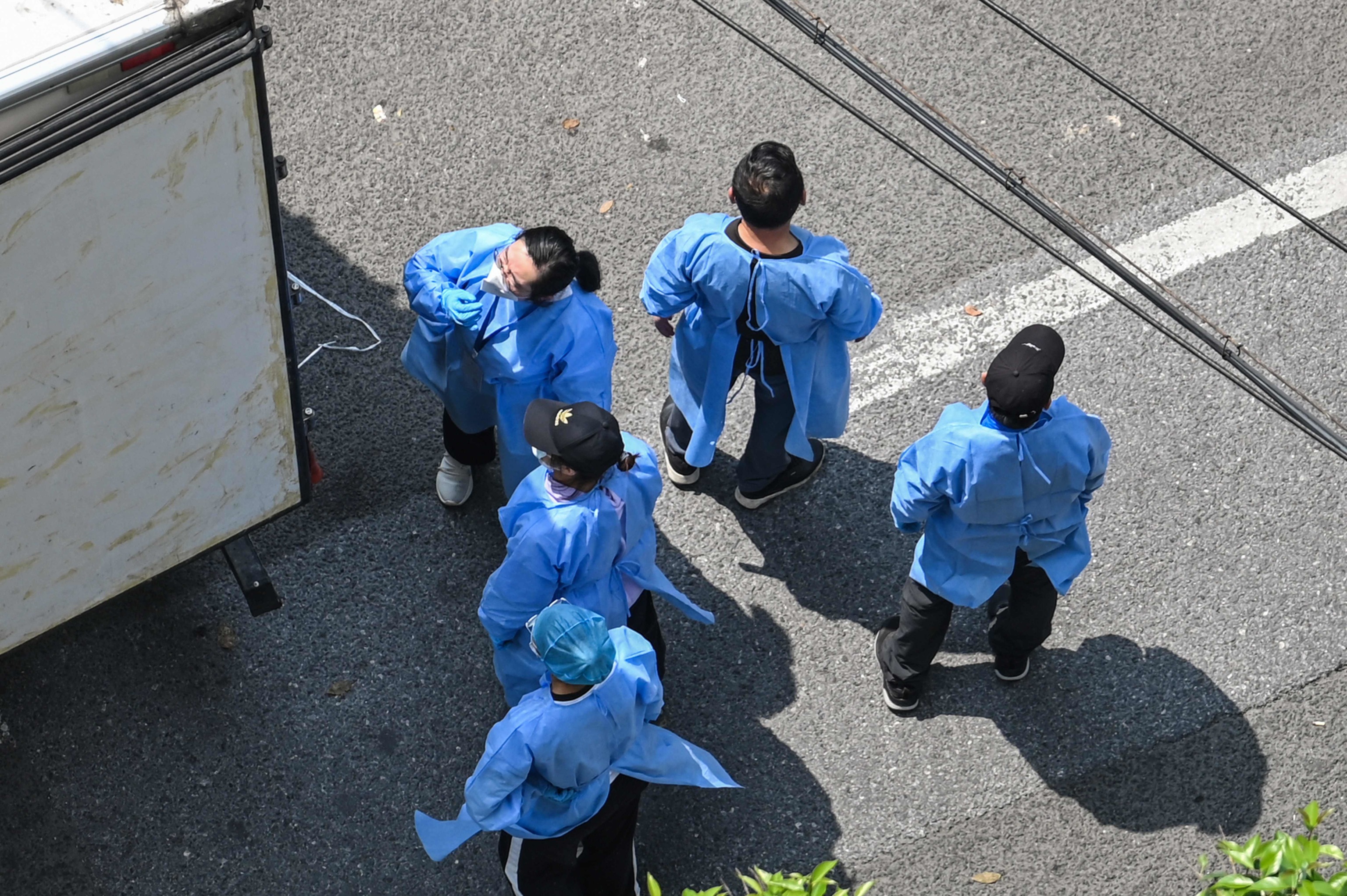 People wearing protective suits unload boxes from a truck in Shanghai.