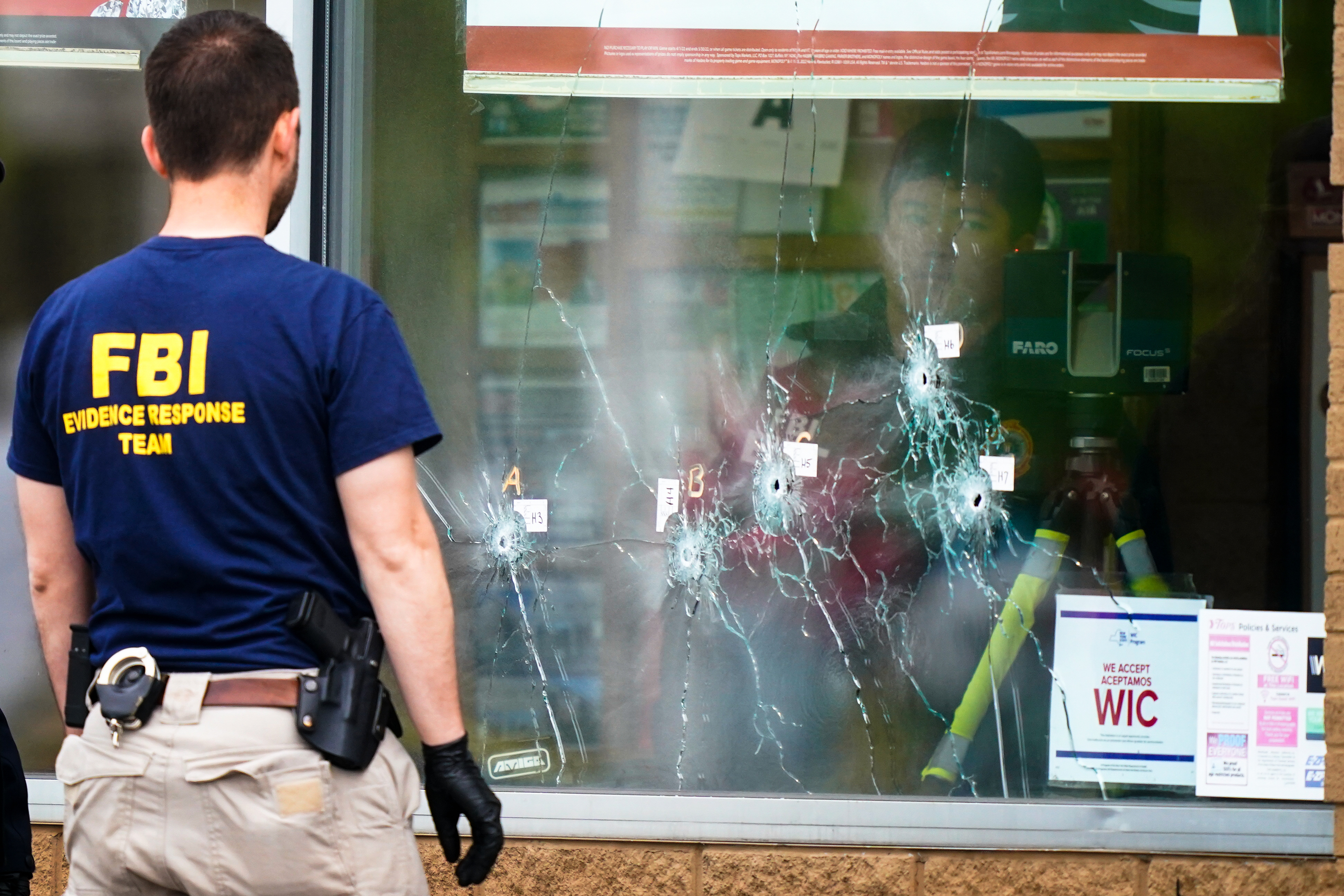 An investigator looks at bullet holes in a Buffalo supermarket.