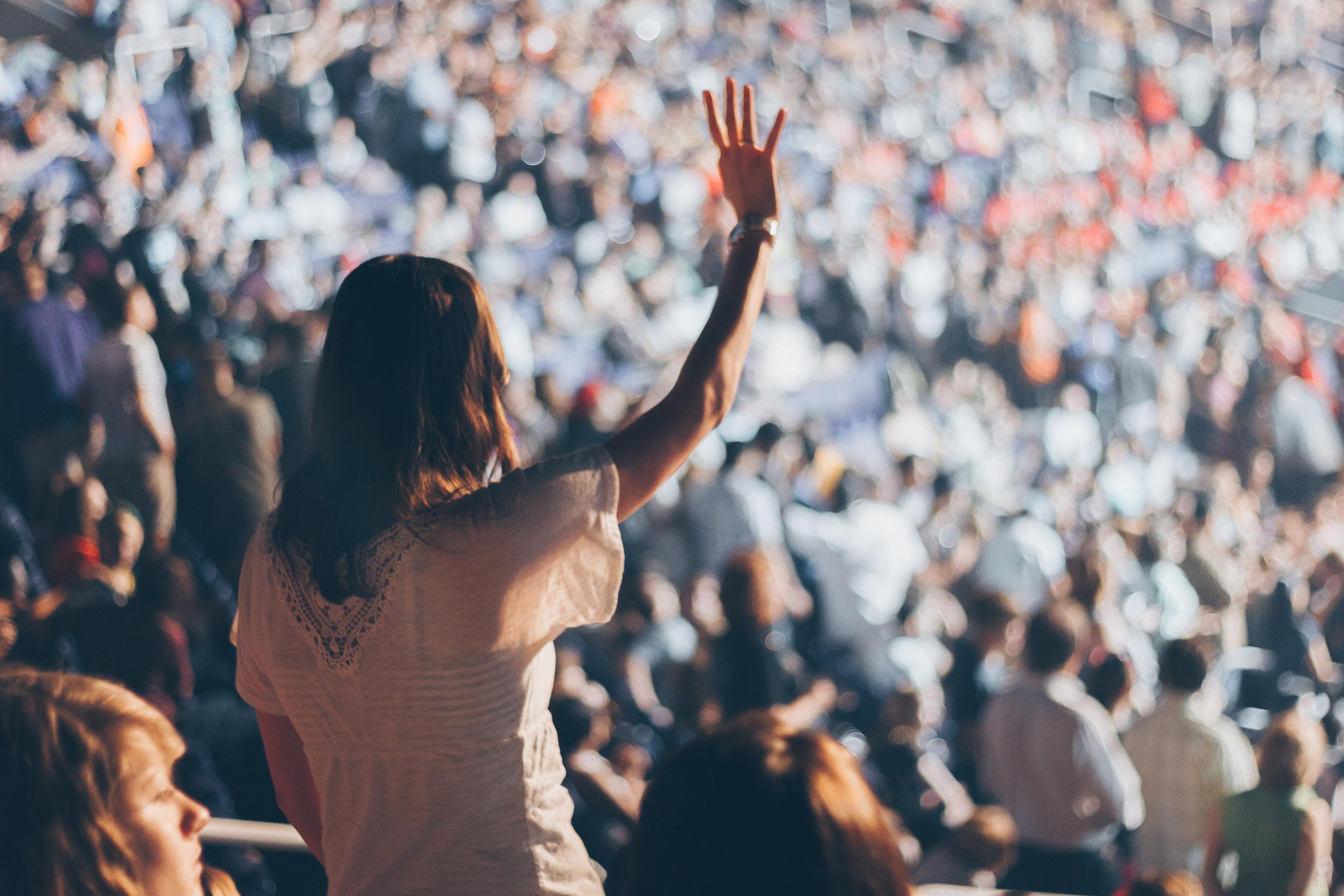 Una mujer levanta la mano junto a una multitud de personas.