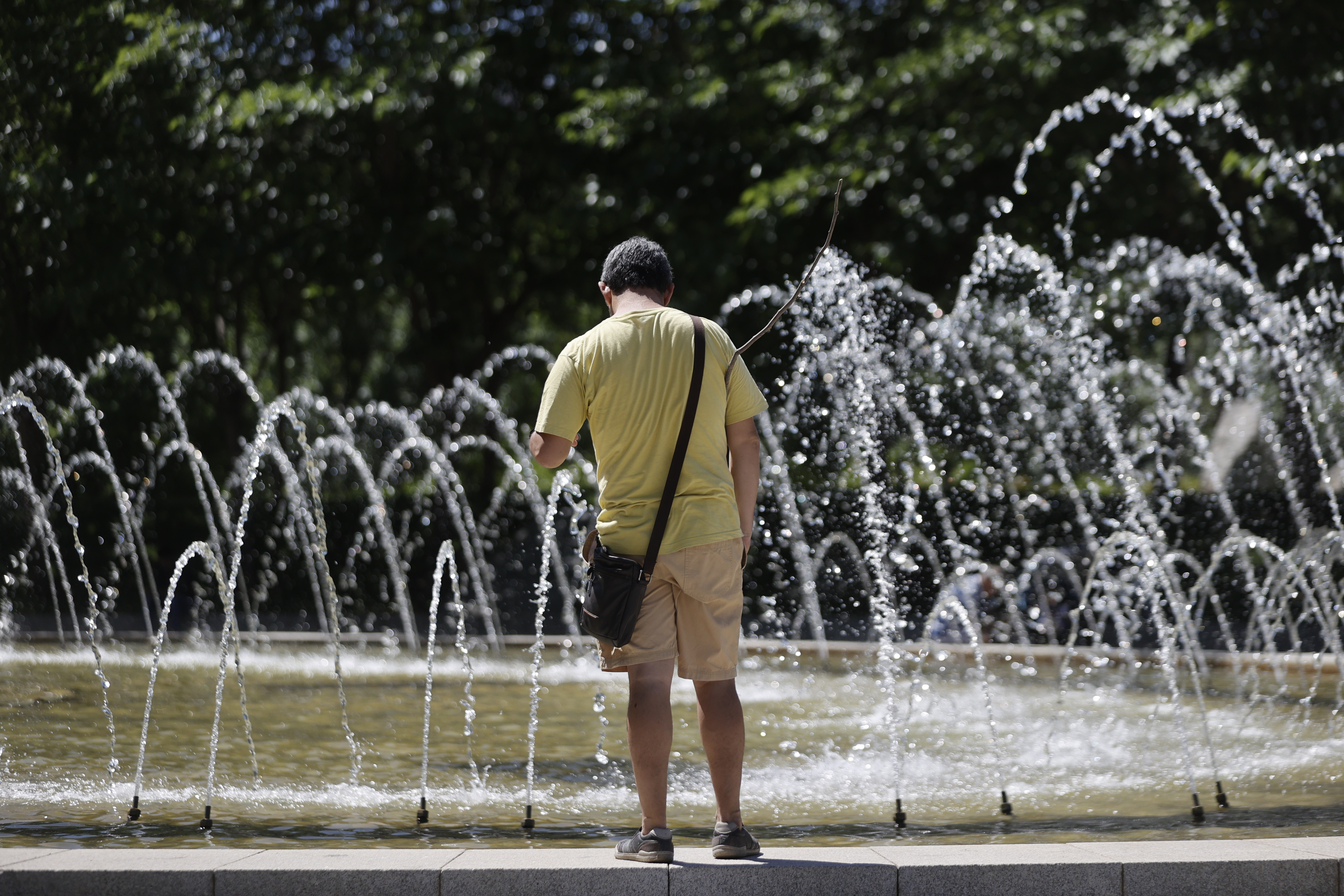 A passerby approaches a fountain in a Madrid park this Tuesday.  scorching heat return