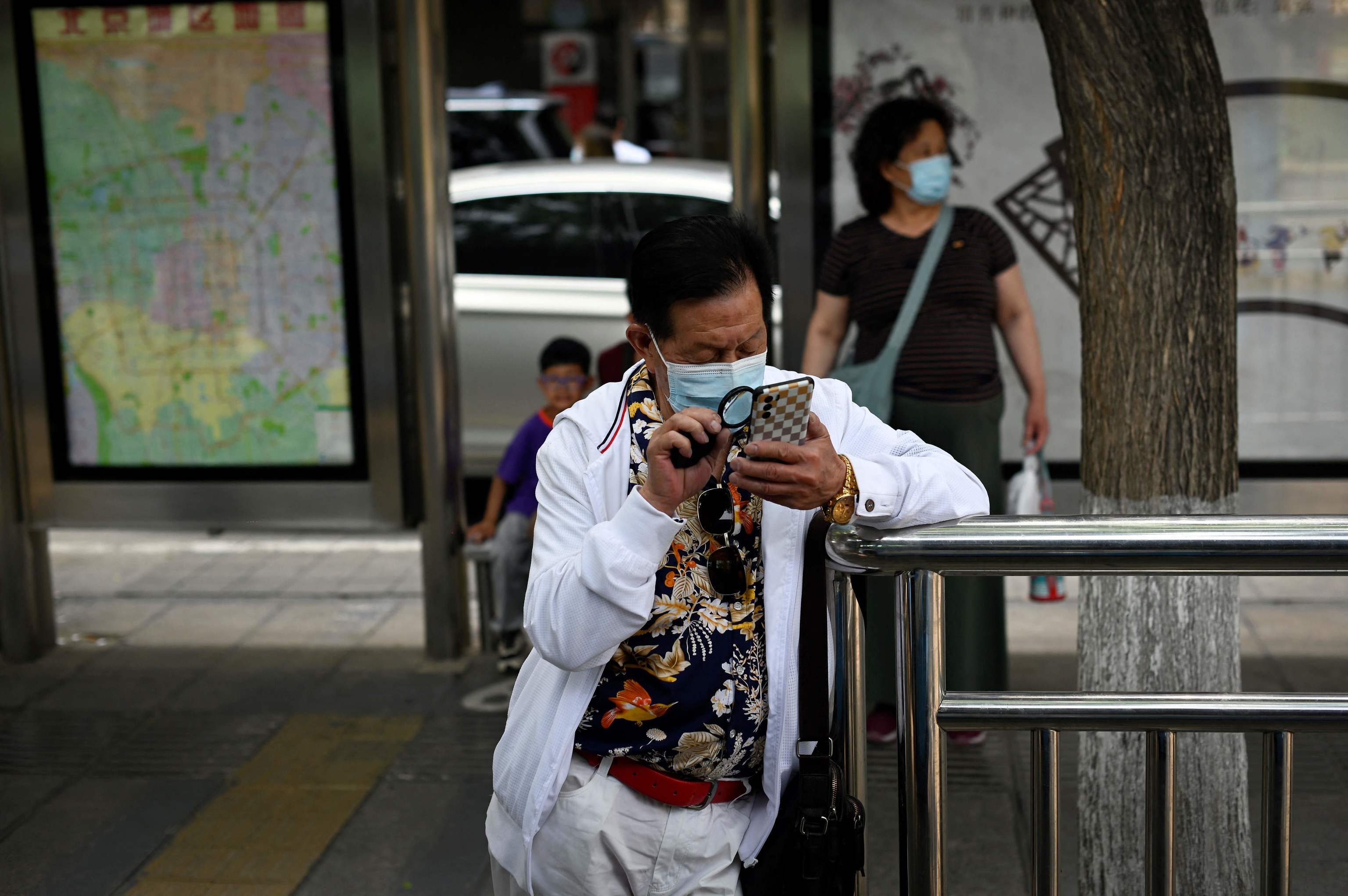 Un hombre lee con lupa su móvil, en Pekín.