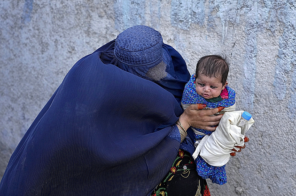 A woman waits for something to eat with her child in Kabul.