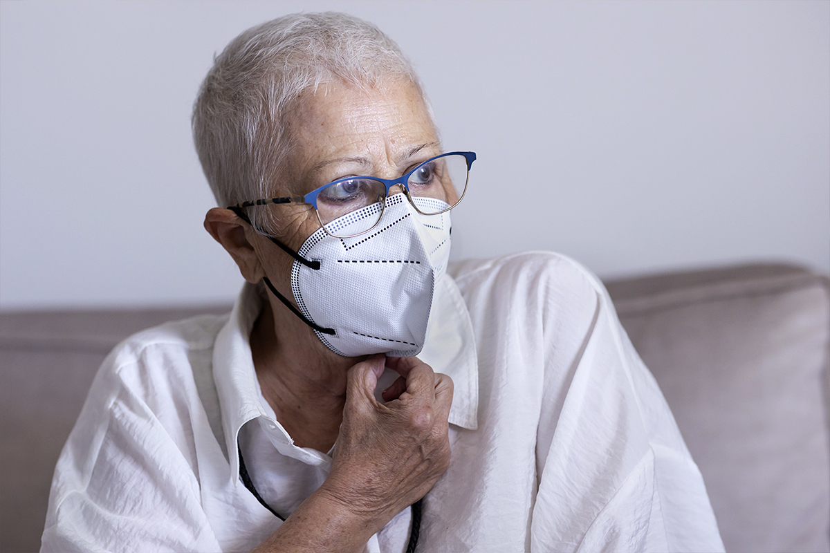 Nieves Robledo, 68 años, enferma de cáncer de vejiga, se protege con una mascarilla en el salón de su piso en Torremolinos.