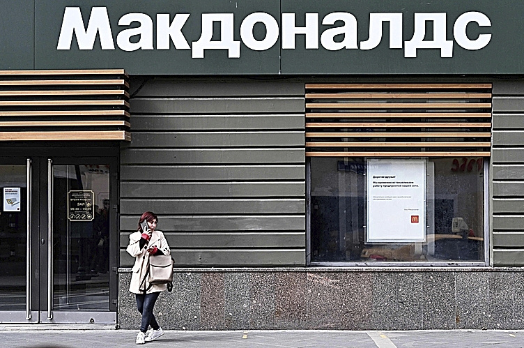 A woman stands next to a closed McDonald's in Moscow.