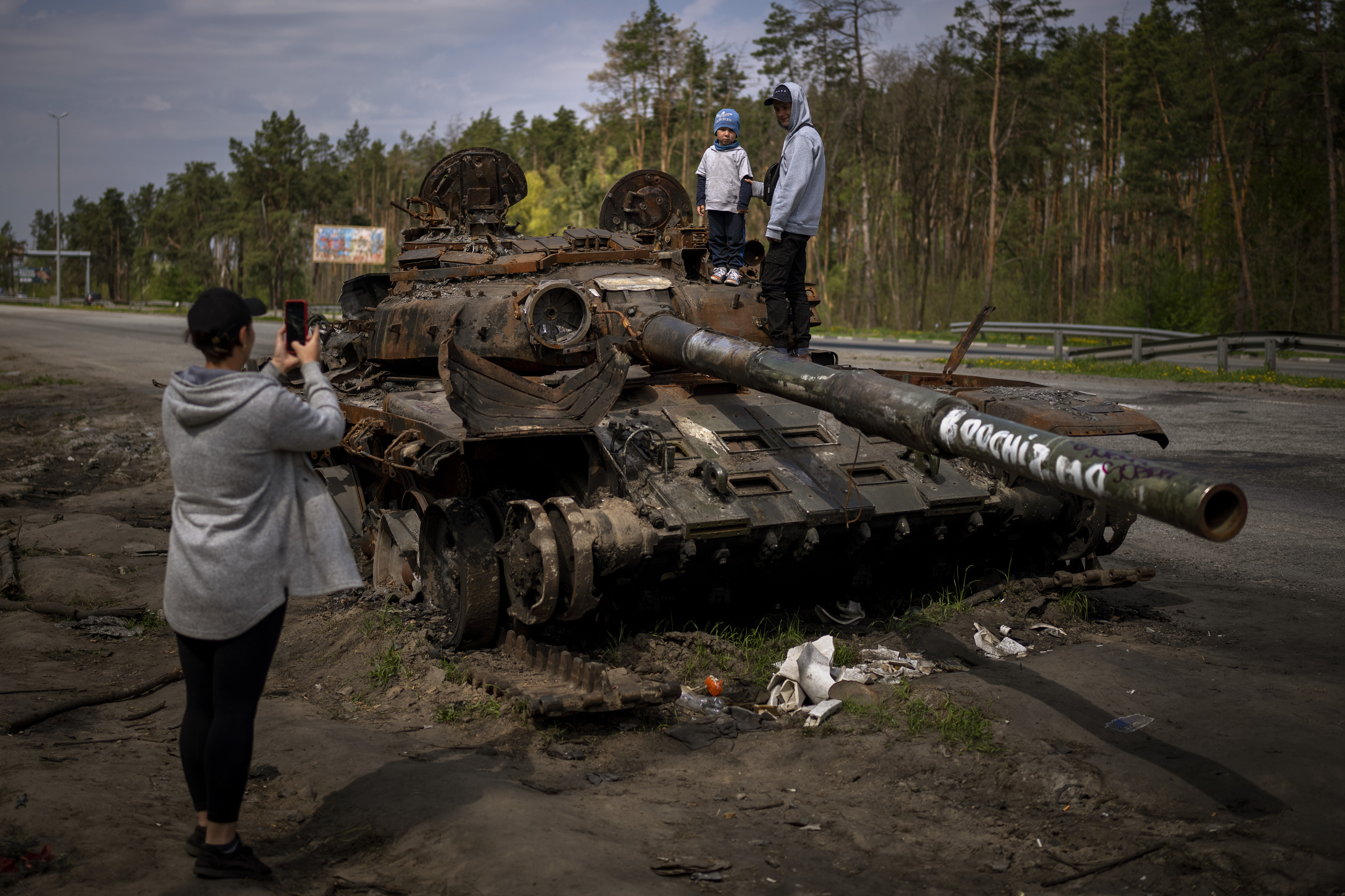 Two brothers take a picture in a destroyed Russian tank near Kyiv.
