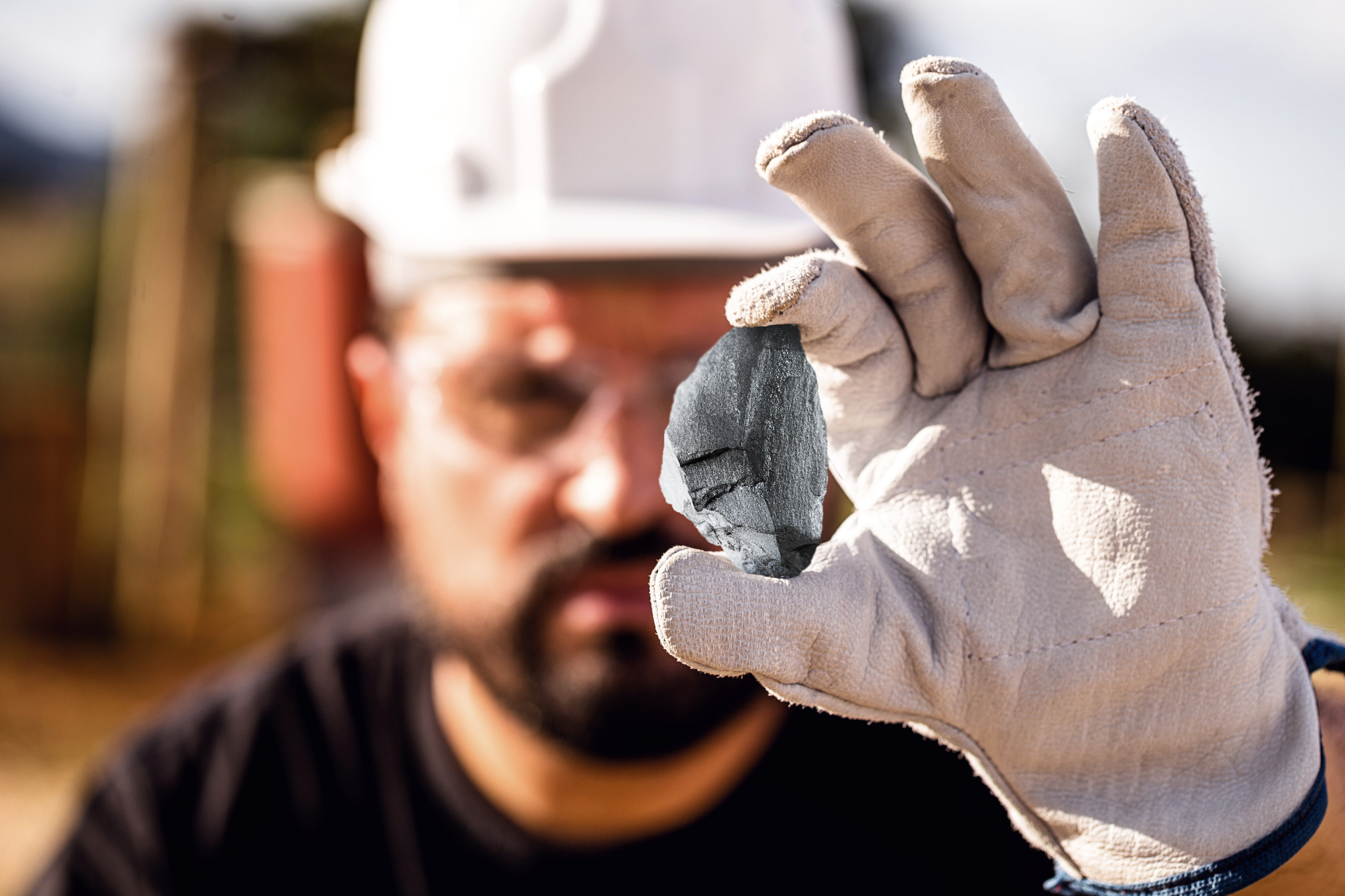 Un operario sostiene un fragmento de mineral de manganeso