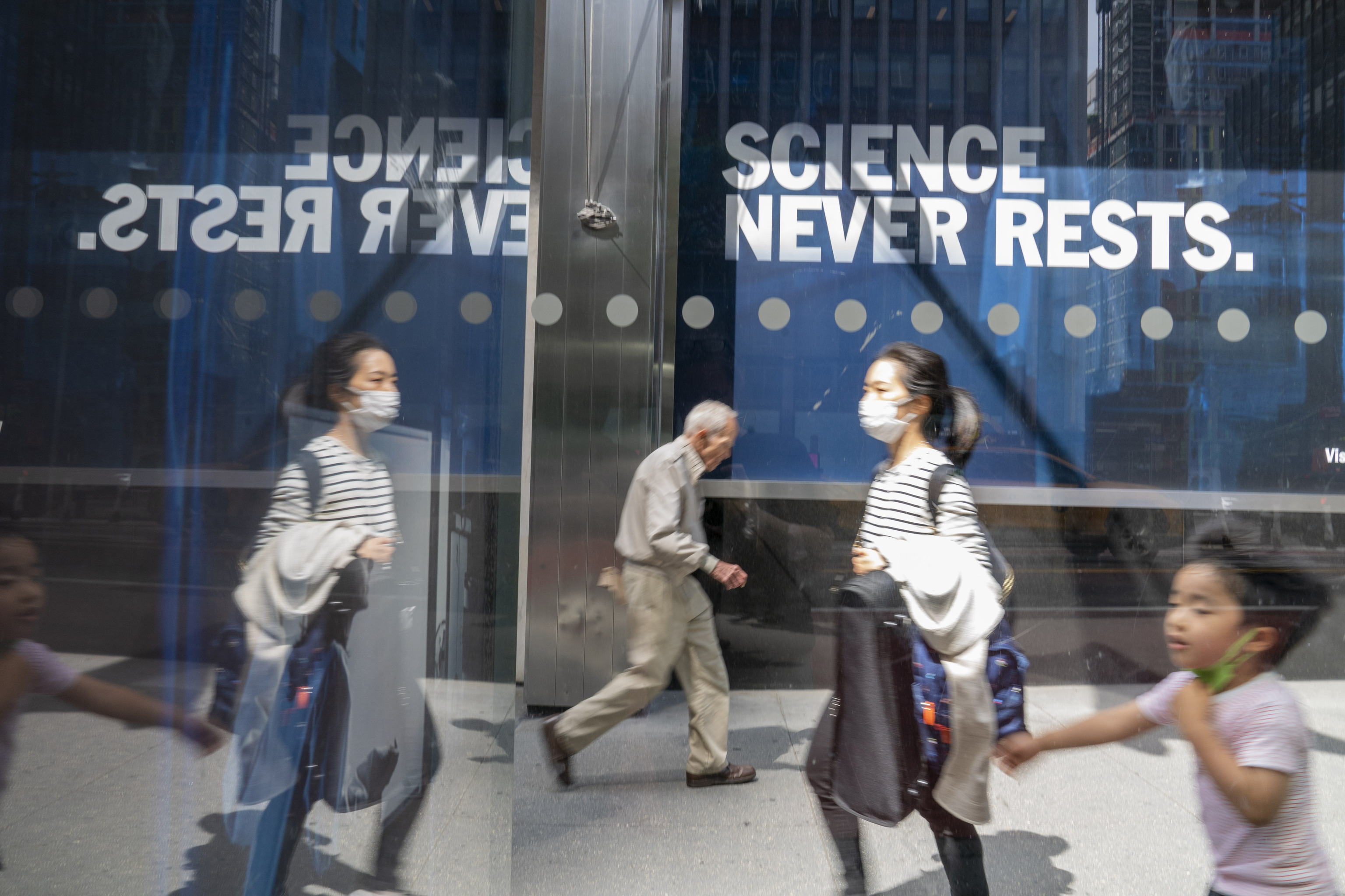 Peatones caminan frente a la sede de Pfizer en Nueva York, donde reza el lema  'La ciencia nunca descansa'.