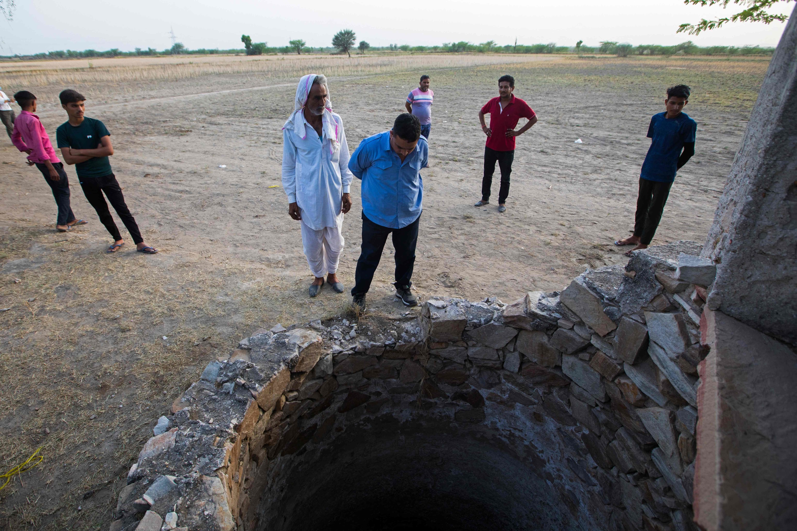 Farmer Sardar Meena (Center L) stands near the well where his three married daughters and two grandchildren were found dead in a well in Dudu village in the Indian state of Rajasthan on May 28.