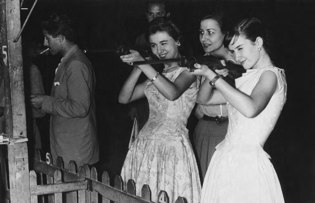 Un par de damas prueban suerte disparando en una feria.