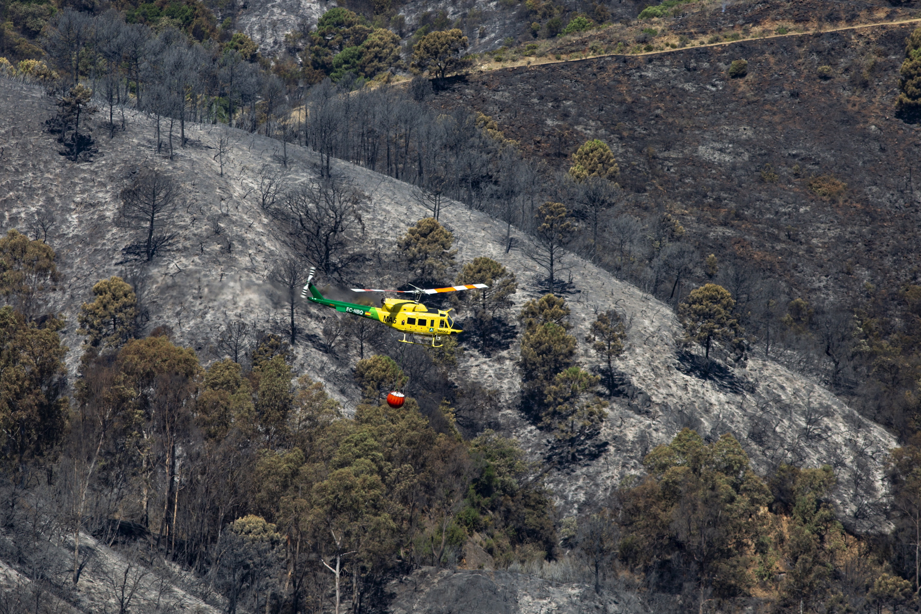 Un helicptero sobrevuela la zona arrasada por las llamas en el incendio de Pujerra.
