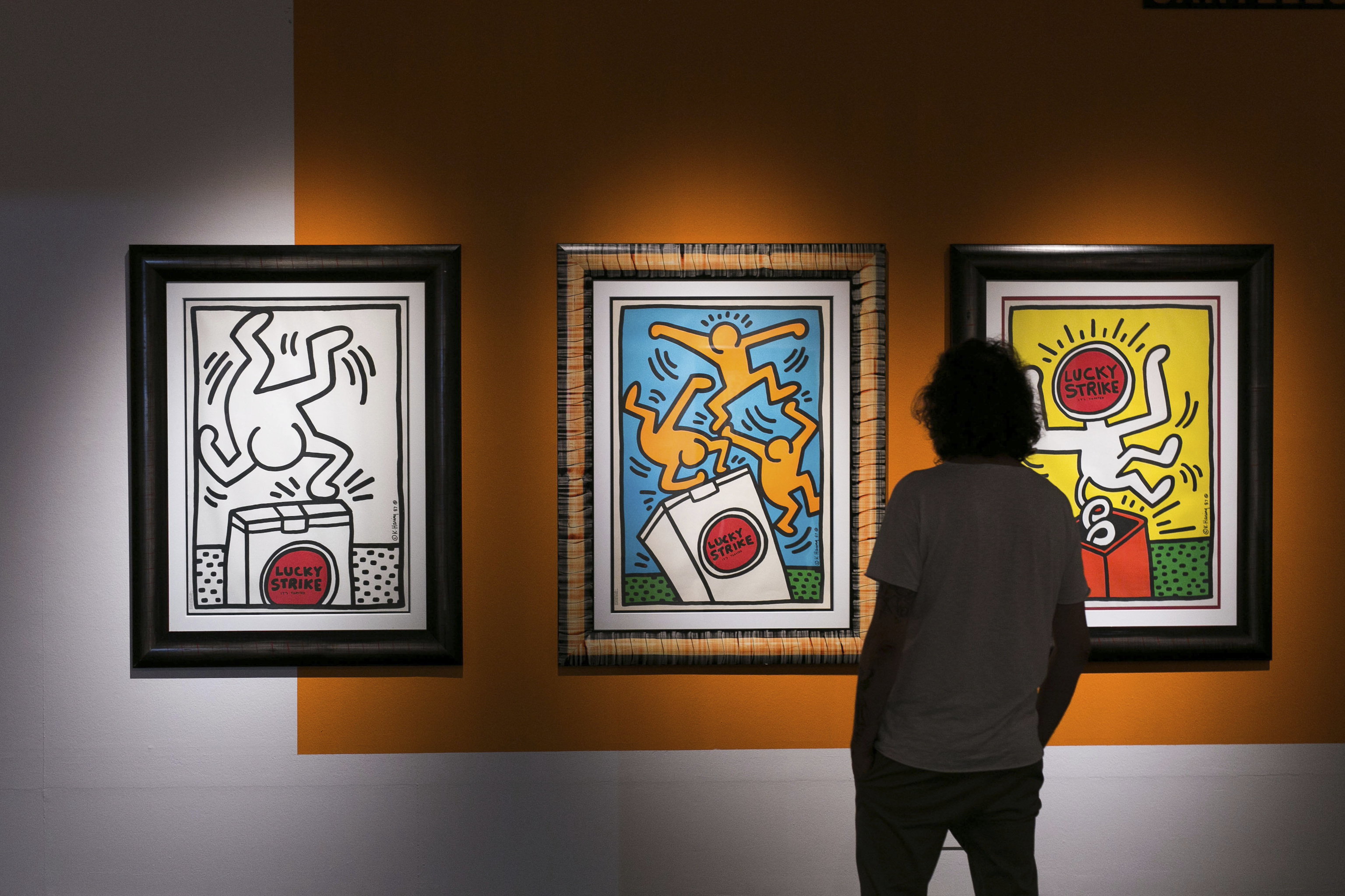 Un visitante contempla varios lienzos del artista Keith Haring.
