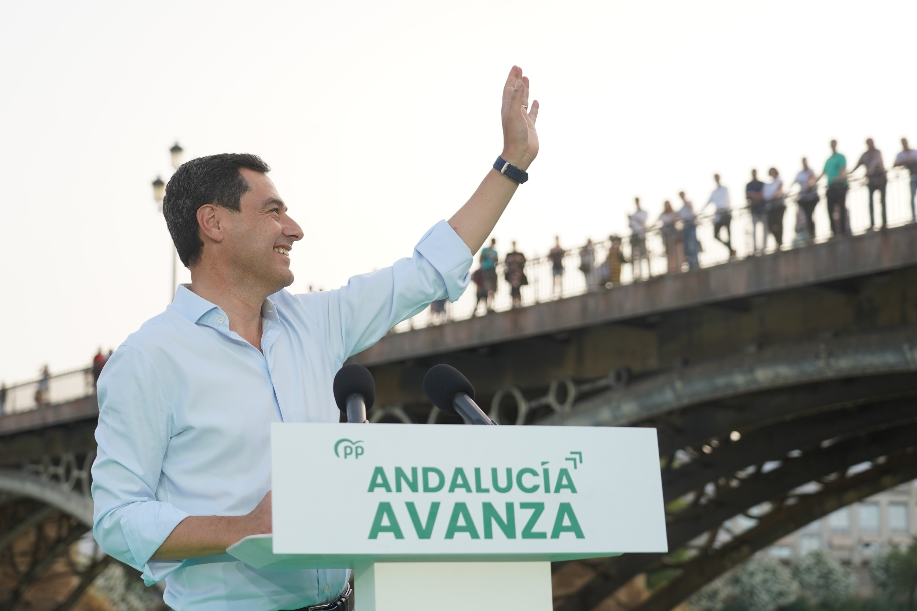 El presidente andaluz y candidato del PP, Juama Moreno, en su mitin de cierre en Sevilla con el puente de Triana al fondo.