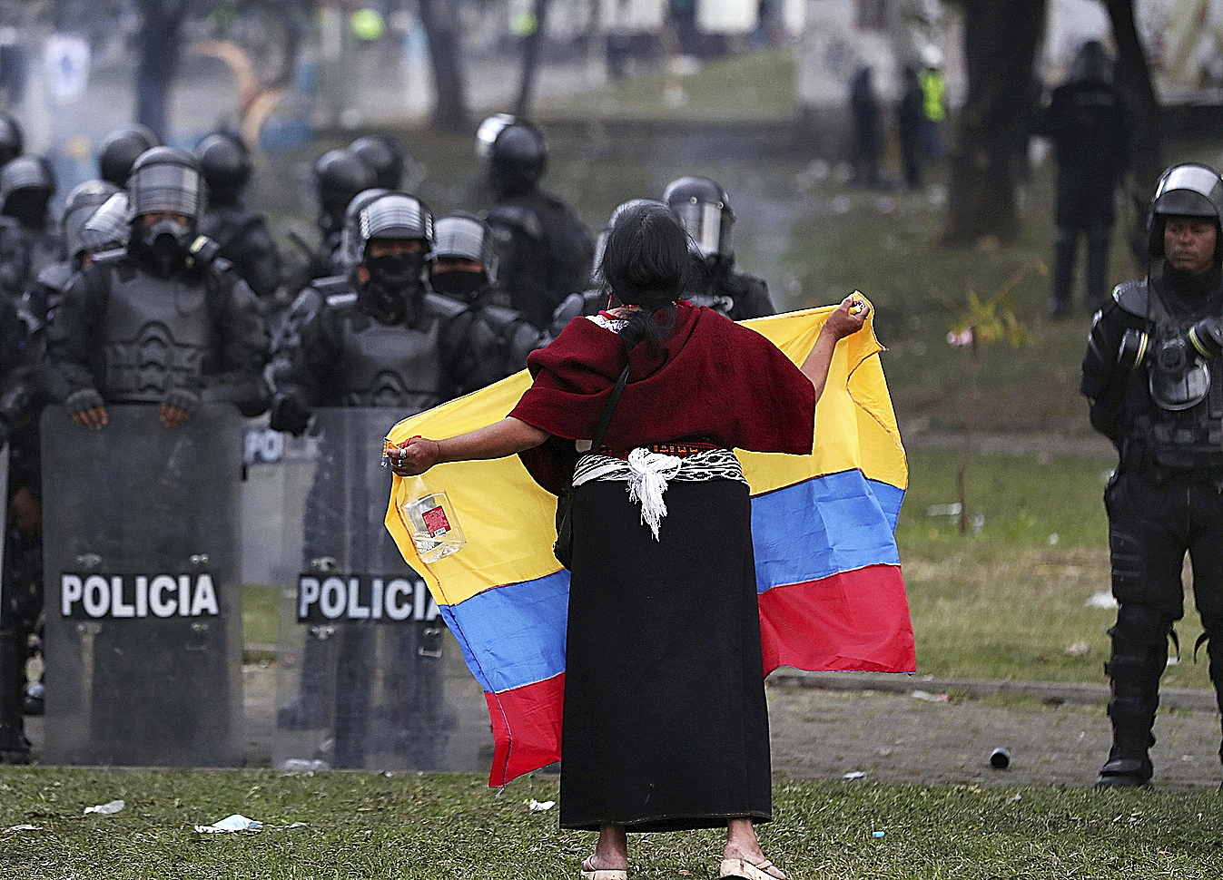Una mujer con la bandera de Ecuador frente a la policía, en Quito.