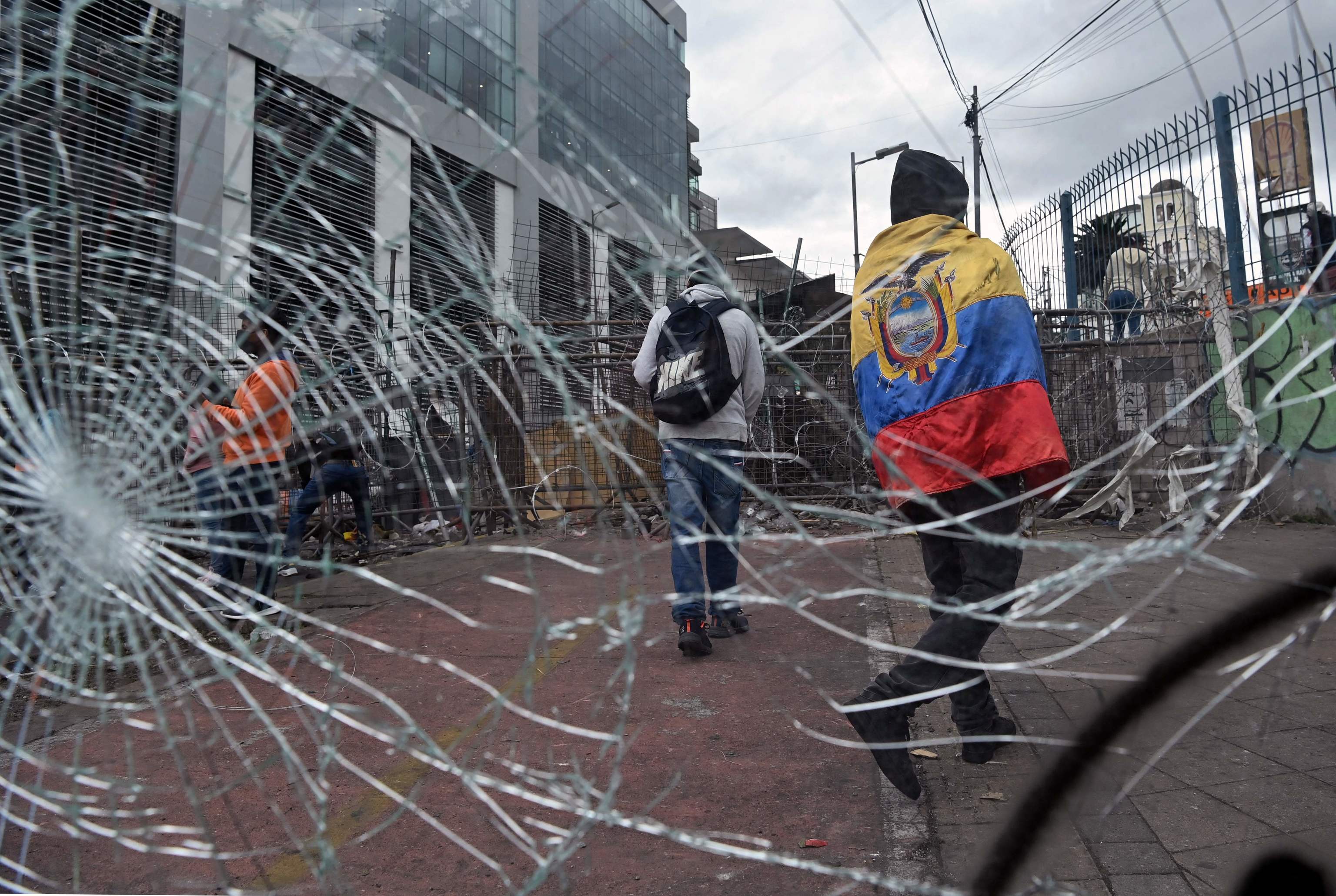 Un indígena envuelto en la bandera de Ecuador camina junto a unos cristales rotos junto a una barricada en los alrededores de la Asamblea Nacional.