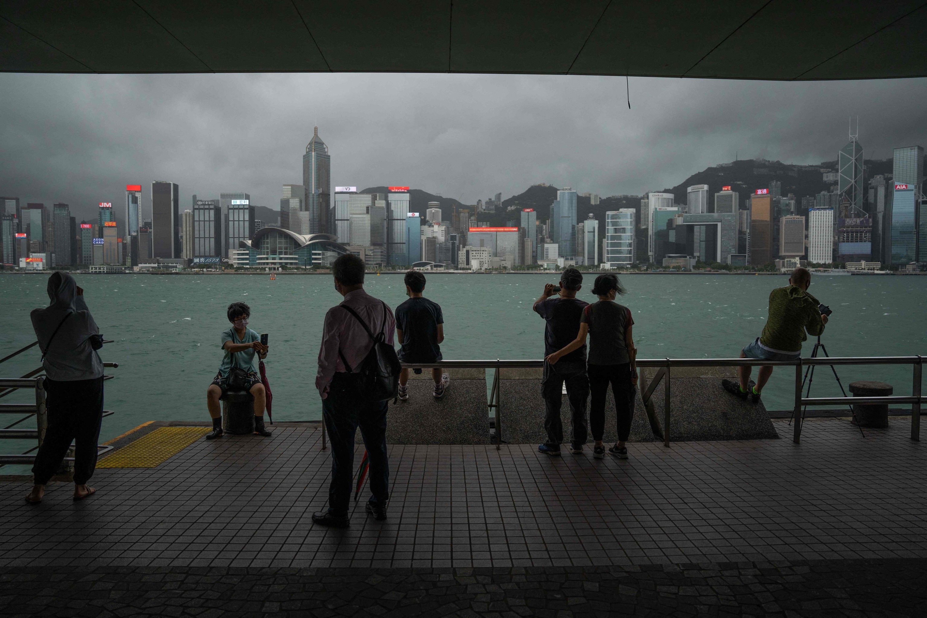 Varias personas hacen fotos al skyline de Hong Kong.