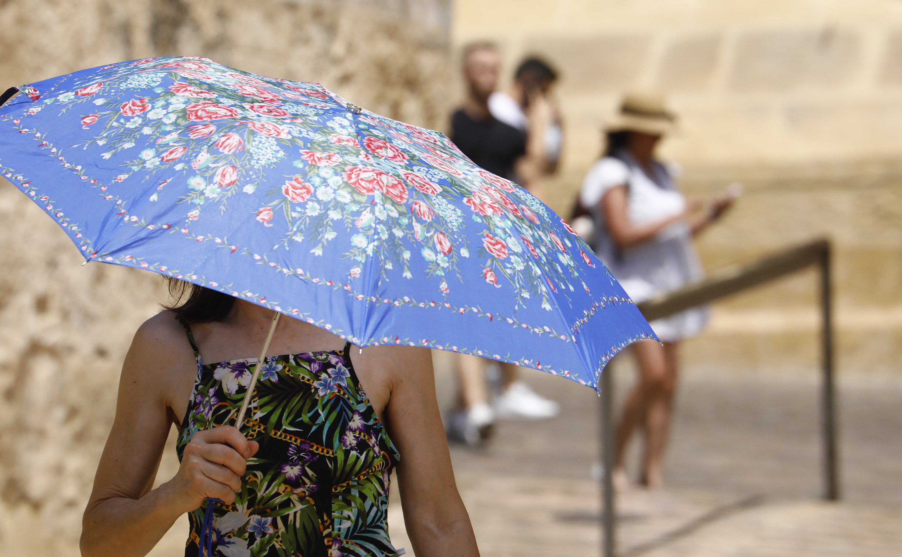 Un turista se protege del calor con un paraguas mientras pasea por las calles de la judería de Córdoba en una jornada de intenso calor donde se esperan llegar a los 37 grados.