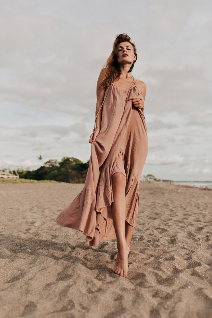ALT: Una modelo en la playa luciendo un vestido largo.