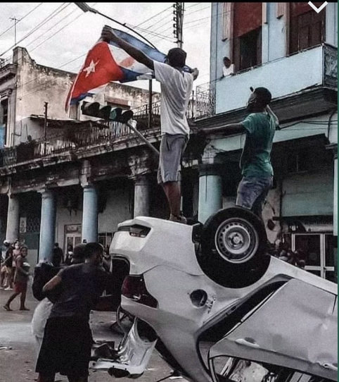 Elas Rizo con la bandera cubana sobre un coche patrulla.