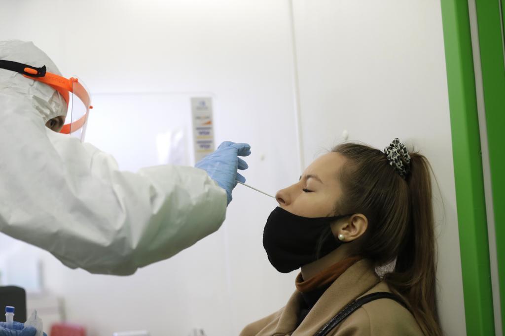 Un sanitario realiza una prueba de antígenos a una mujer.