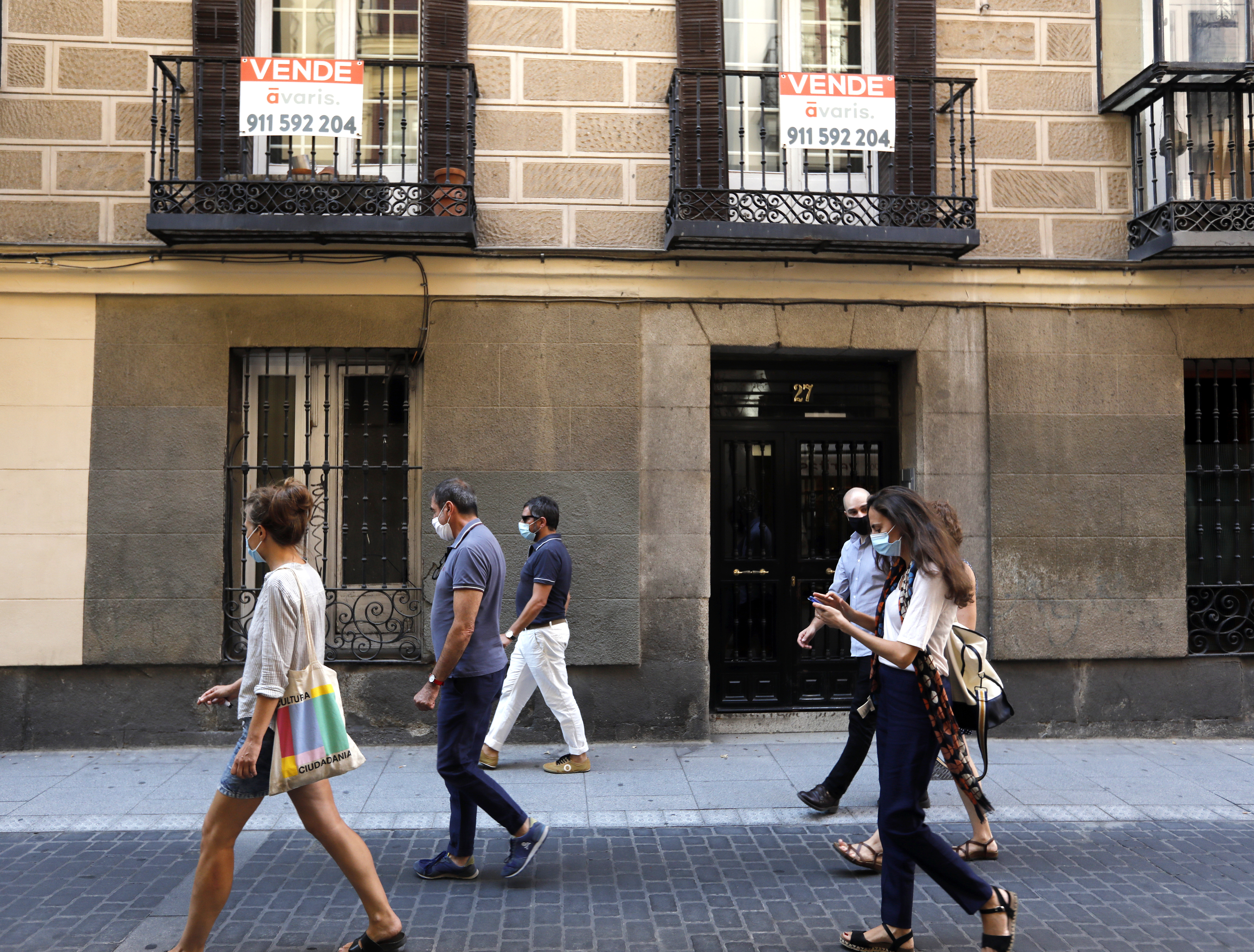 Un grupo de personas camina frente a una vivienda en venta en el centro de Madrid.