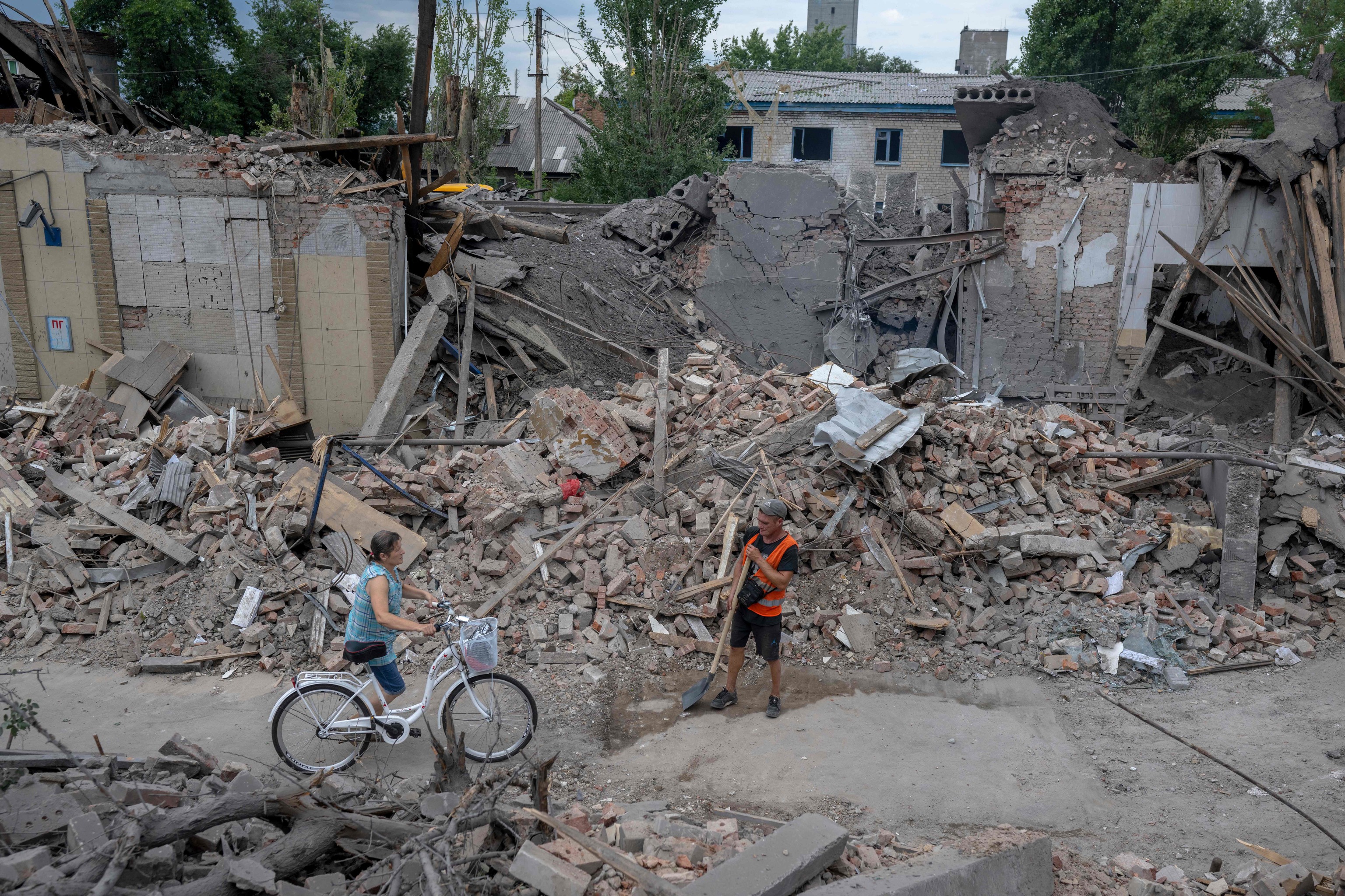 Una mujer pasa con su bicicleta ante un edificio destruido en Toretsk
