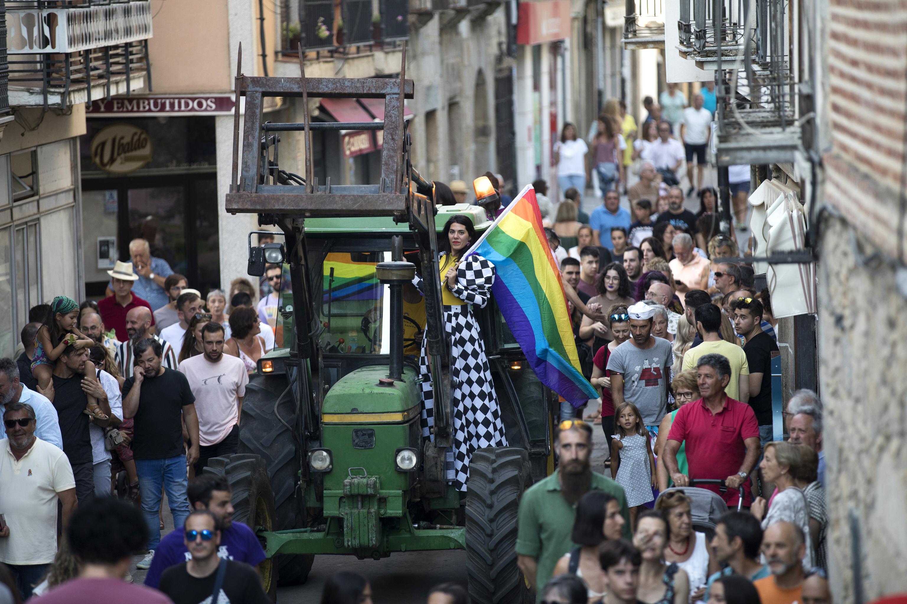 Patricia Galván llegando al centro del pueblo con la bandera del orgullo y rodeada de los abulenses.