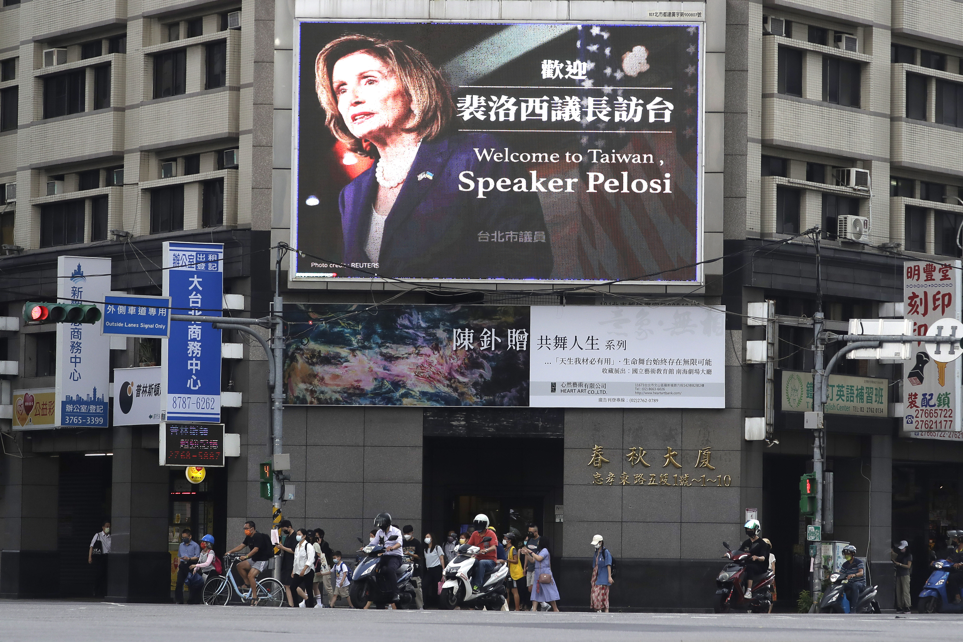 Viandantes en Taipei frente a un cartel que da la bienvenida a Nancy Pelosi a Taiwan, el 3 de agosto de 2022.
